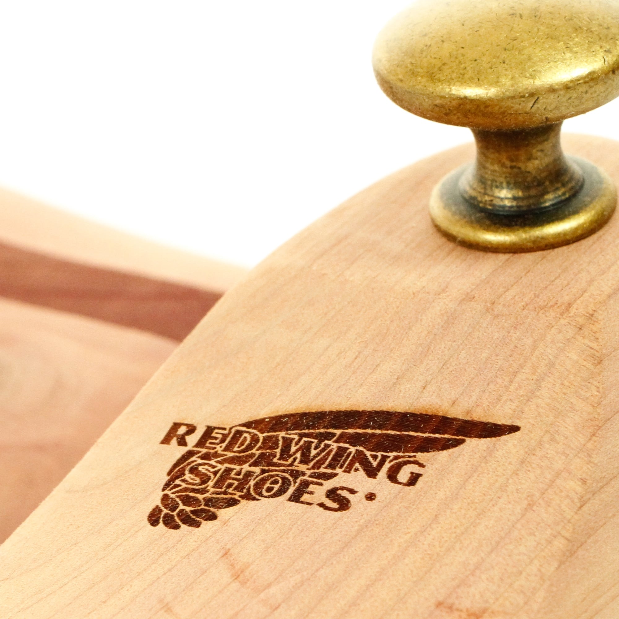Close-up of a shoe tree, highlighting the 'Red Wing Shoes' logo and brass knob.