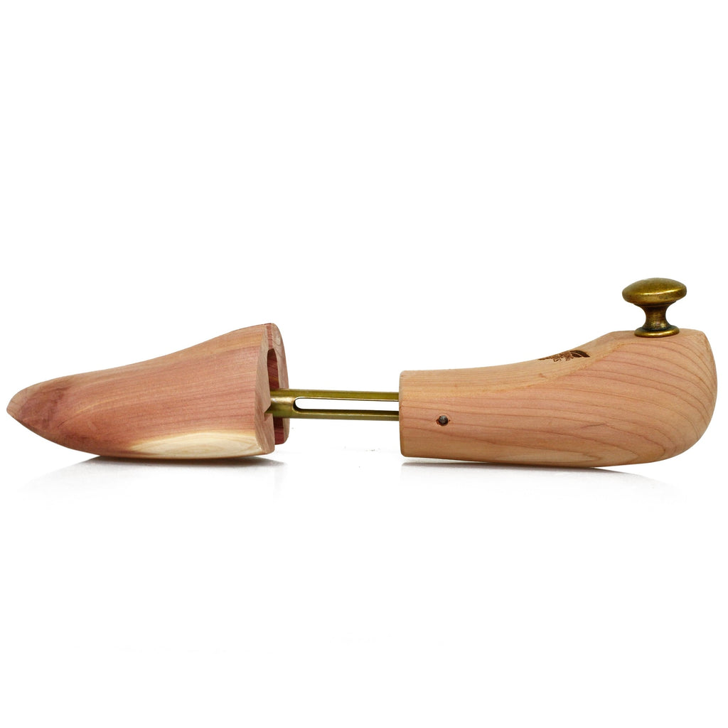 Side view of a single cedar wood shoe tree with brass hardware, extended.