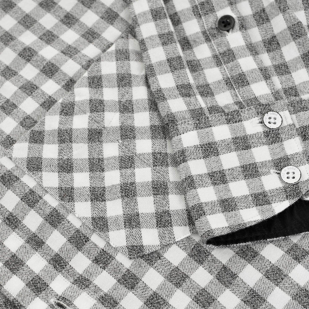 Close-up of the front pocket and buttons on a men's grey and white gingham shirt.