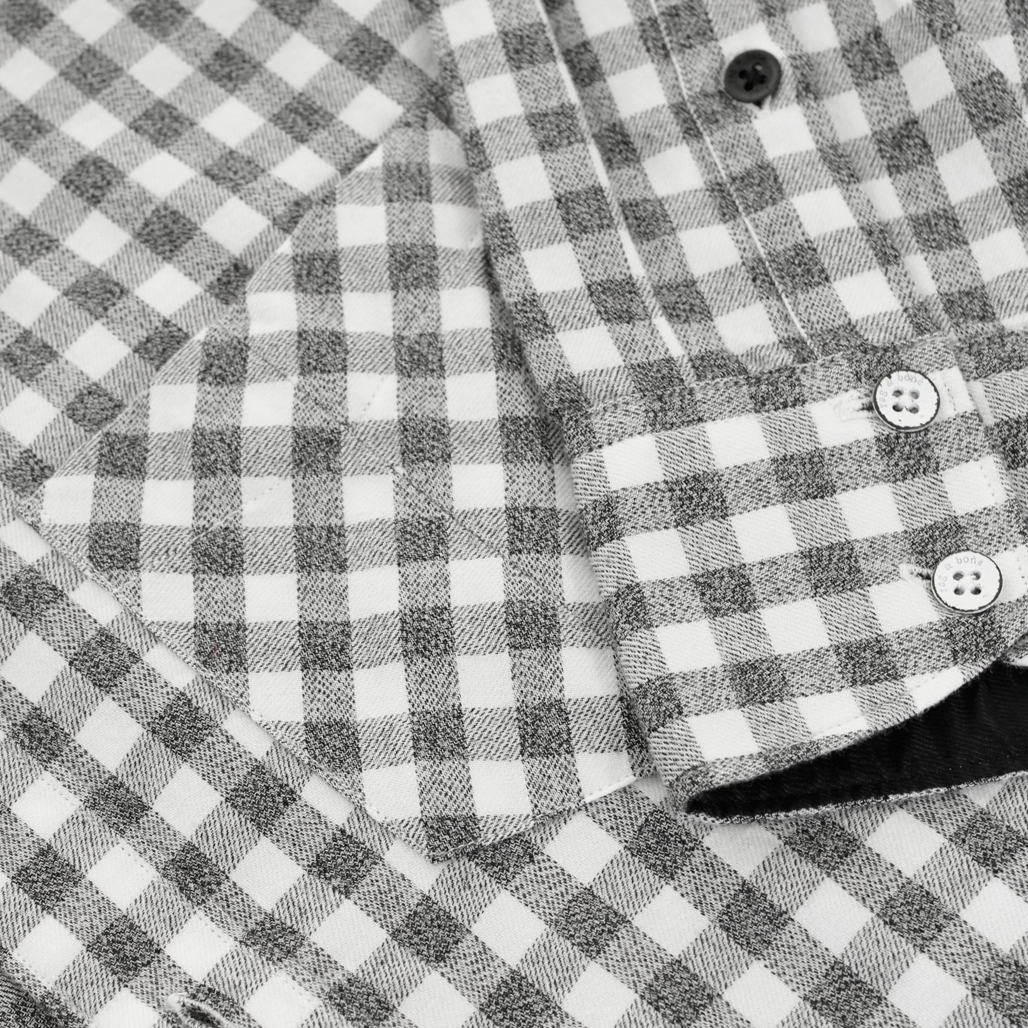 Close-up of the front pocket and buttons on a men's grey and white gingham shirt.