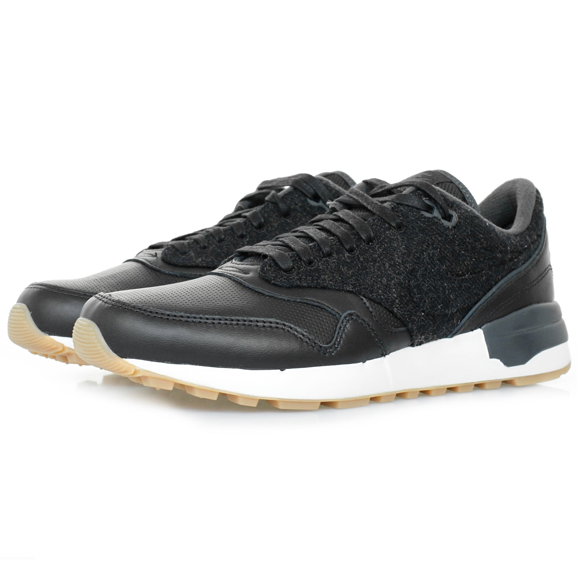 A pair of black trainers with a textured upper and white soles, viewed from an angle.