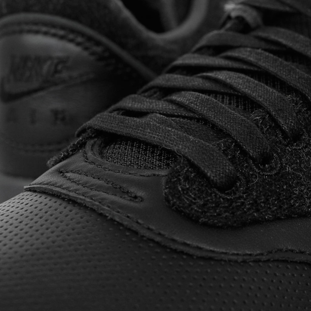 A close-up of the laces and perforated detail on a black trainer.