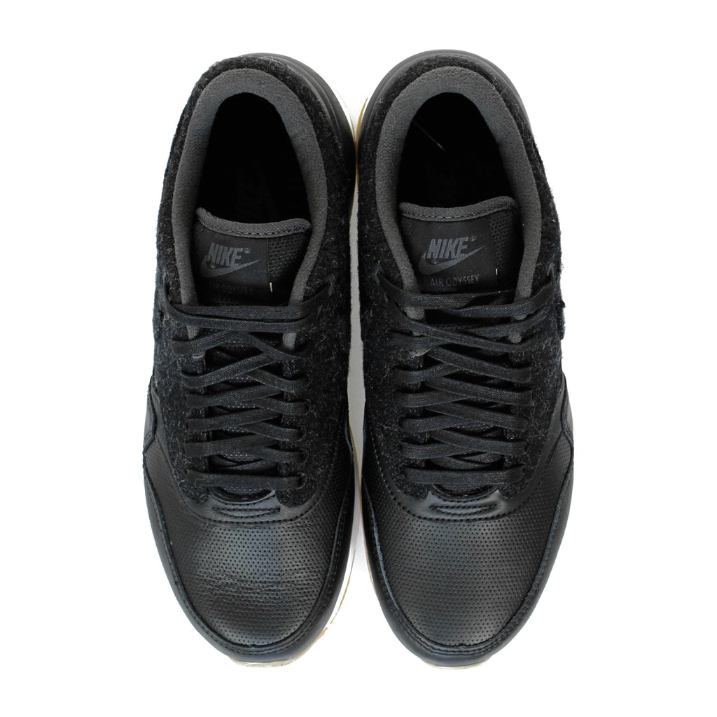 A pair of black trainers with textured uppers and white soles, viewed from above.