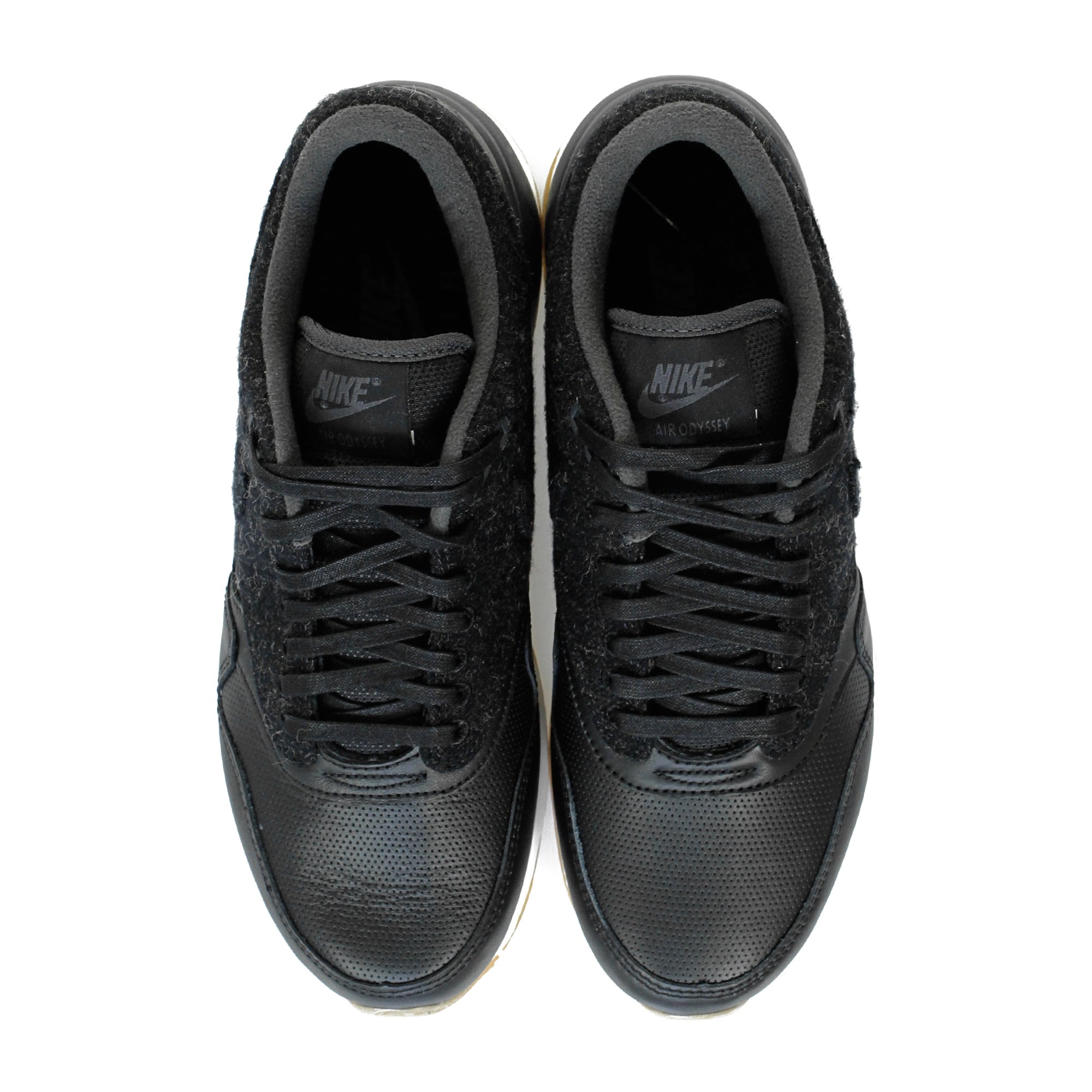A pair of black trainers with textured uppers and white soles, viewed from above.