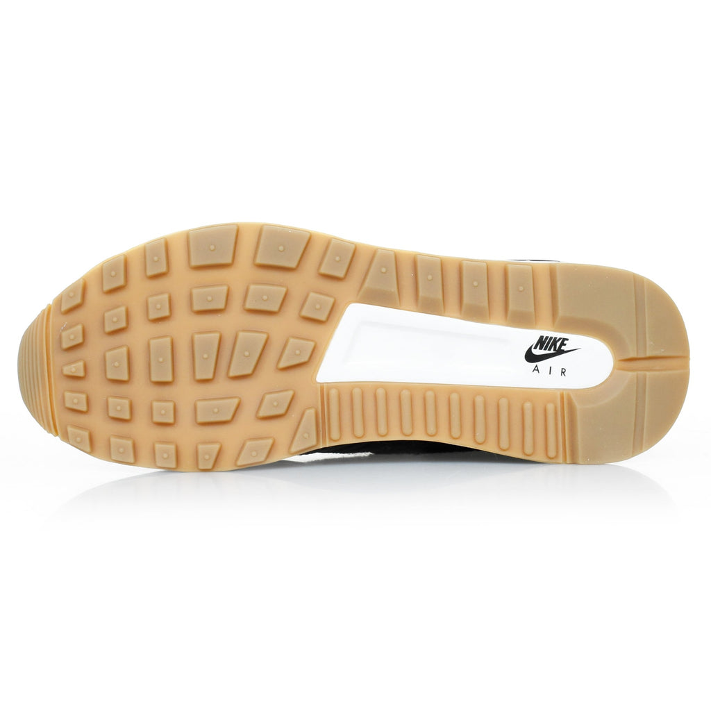 The textured rubber sole of a black trainer with a white central section.
