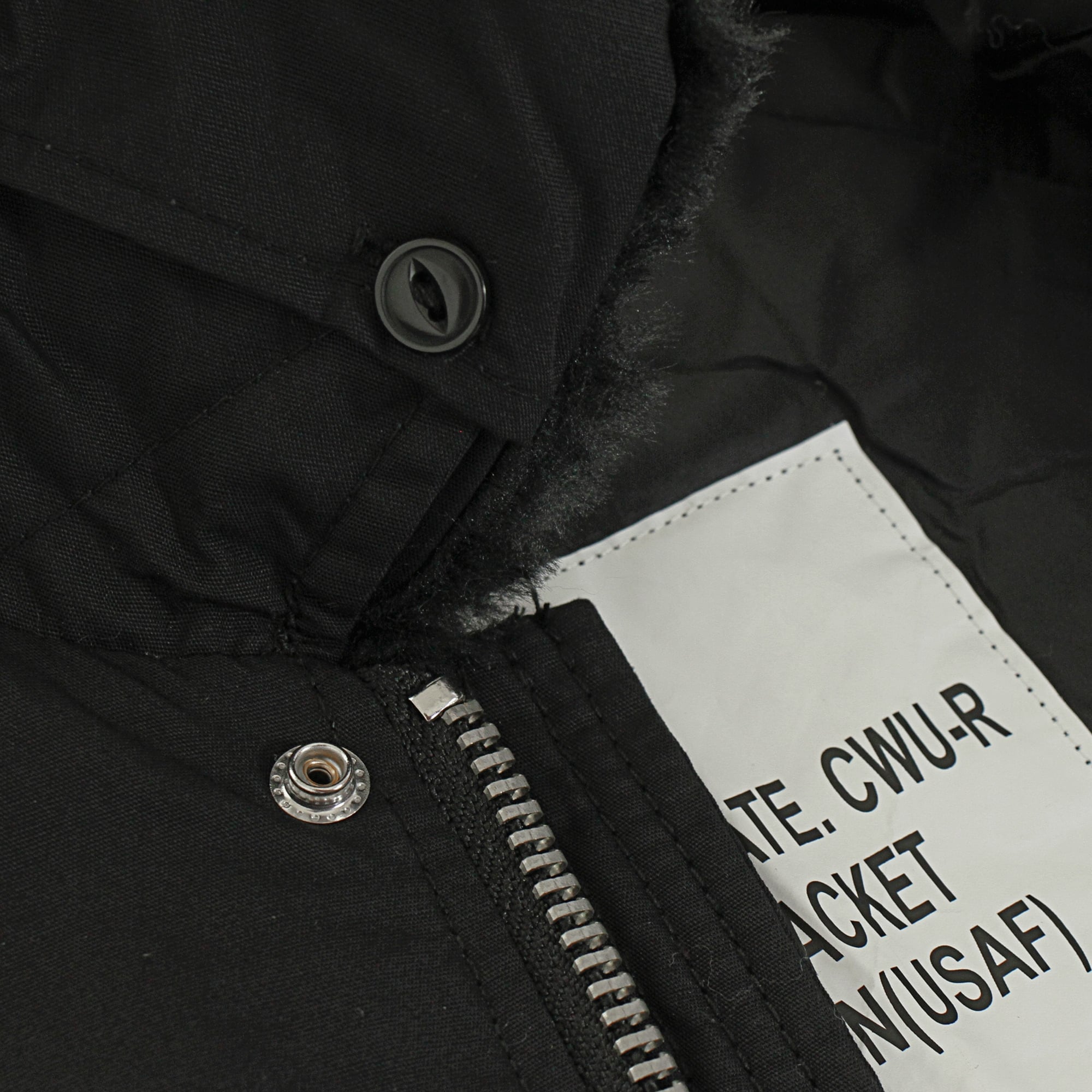 A close-up of the black bomber jacket's zipper, button, and inner label.