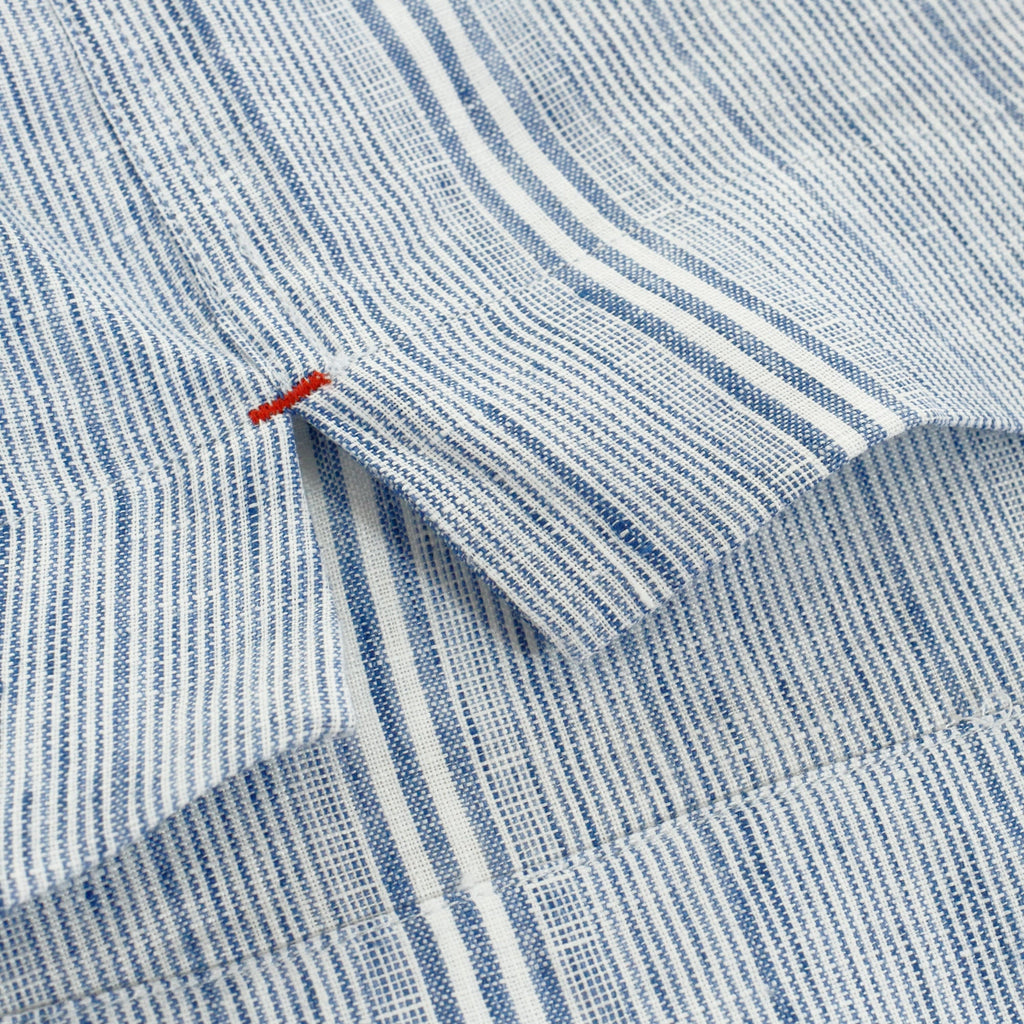 Close-up of the shirt's fabric, showing a white stripe and small orange stitching detail.