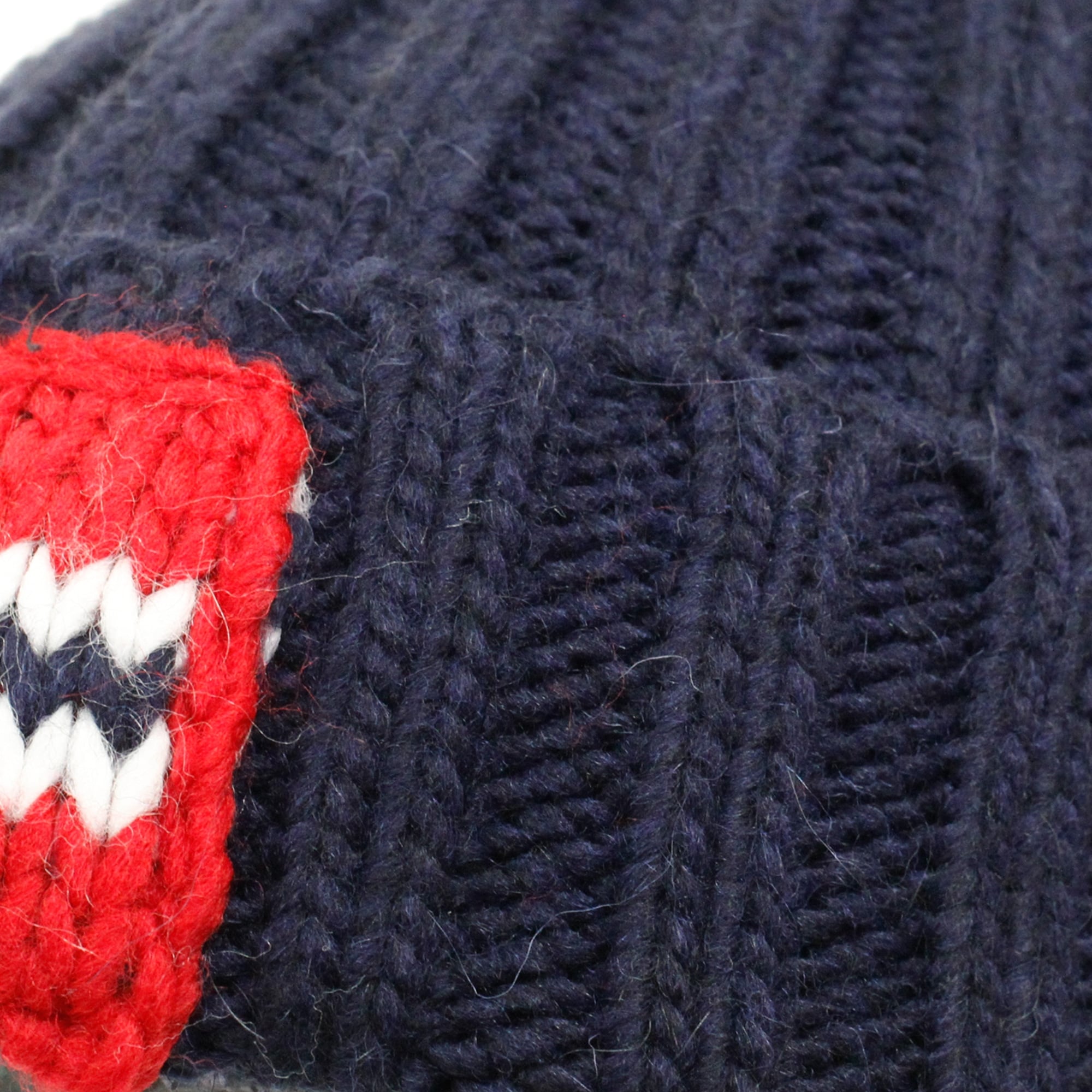 Close-up of a dark blue knitted hat with a red, white, and blue flag emblem.