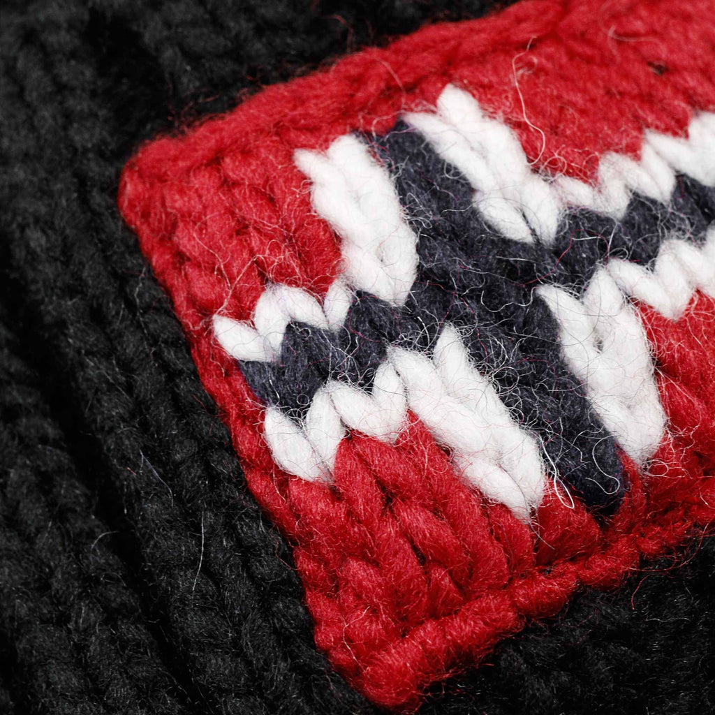 A close-up view of the knitted Norwegian flag patch on a black bobble hat.
