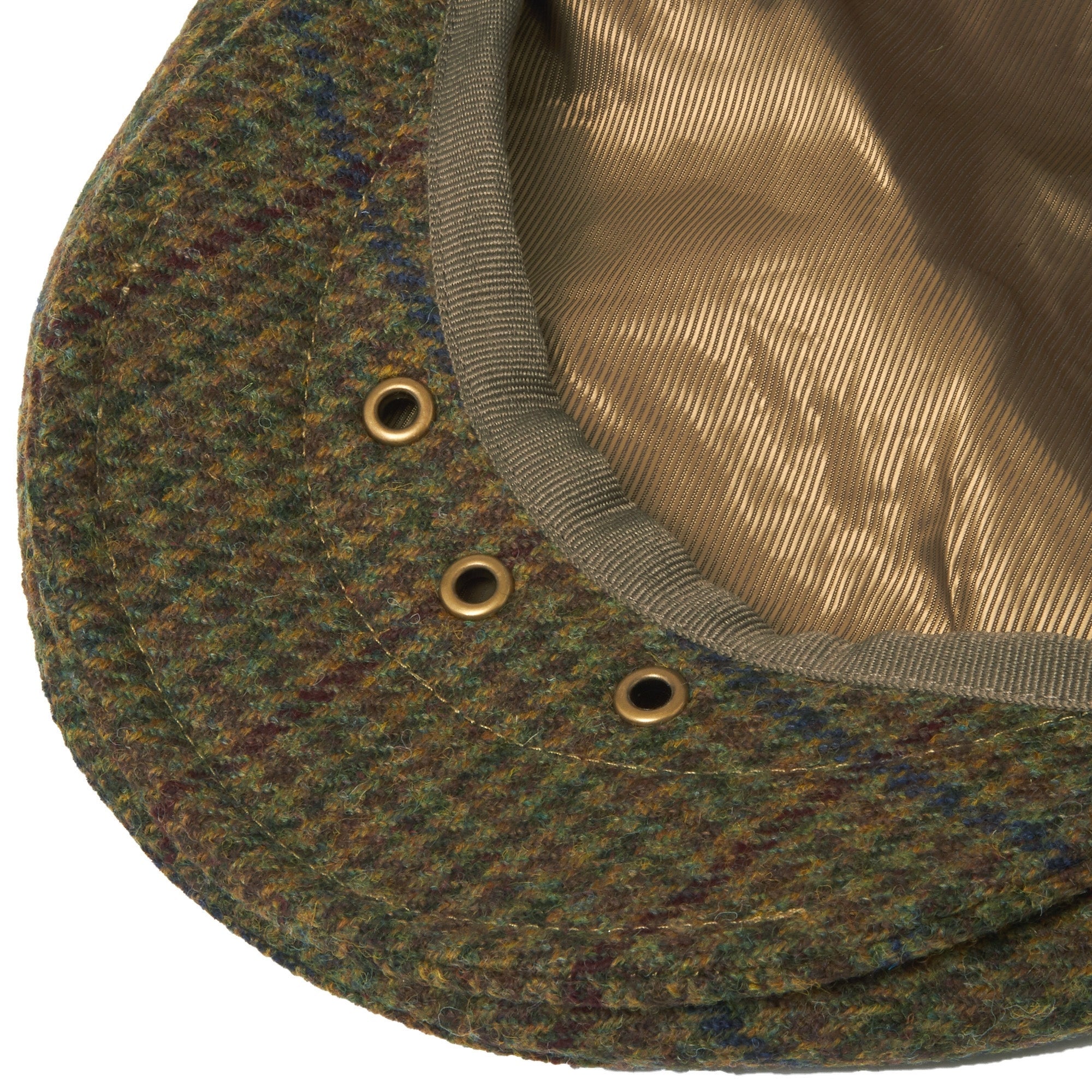 Close-up of the underside of an olive checked flat cap, showing eyelets and lining.