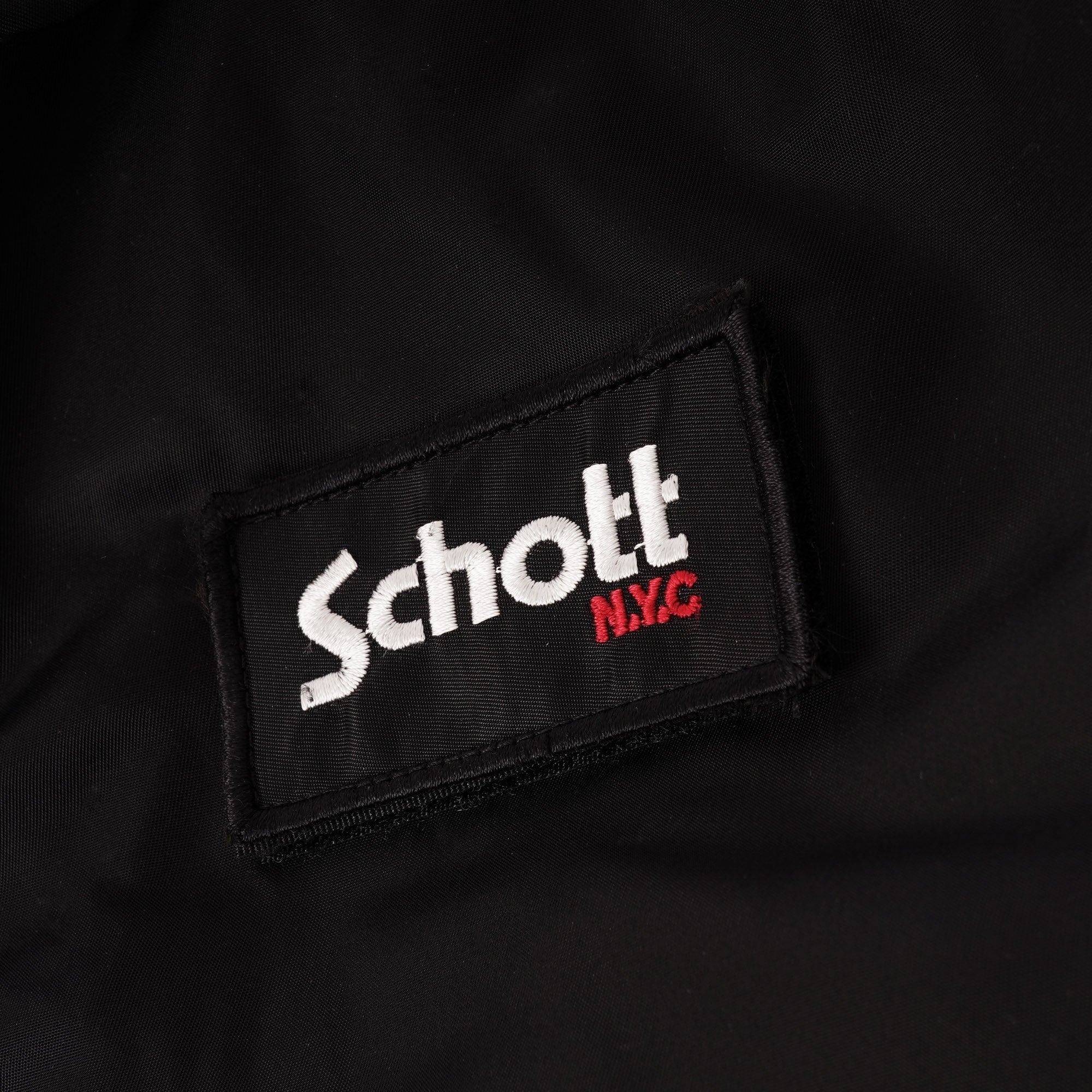A close-up of the 'Schott N.Y.C' logo patch on a black jacket.