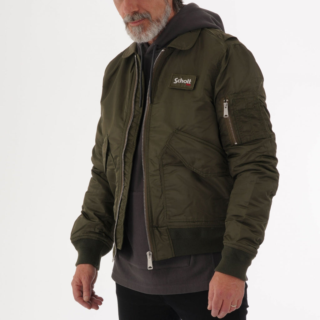 Side view of a man wearing a khaki bomber jacket over a grey hoodie.