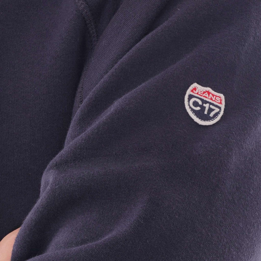 Close-up of the C17 Jeans patch on the sleeve of the navy hoodie.