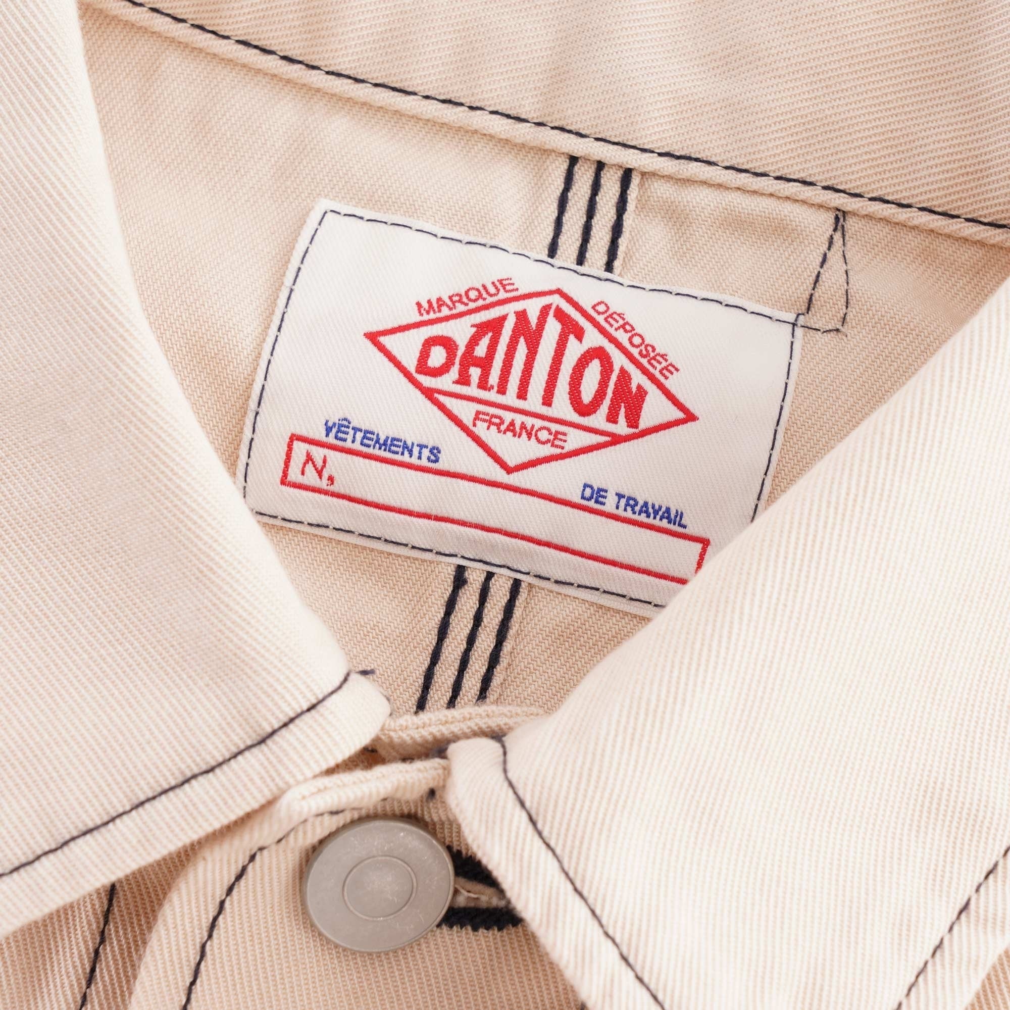 Close-up of the red and white Danton brand label on a beige jacket's collar.