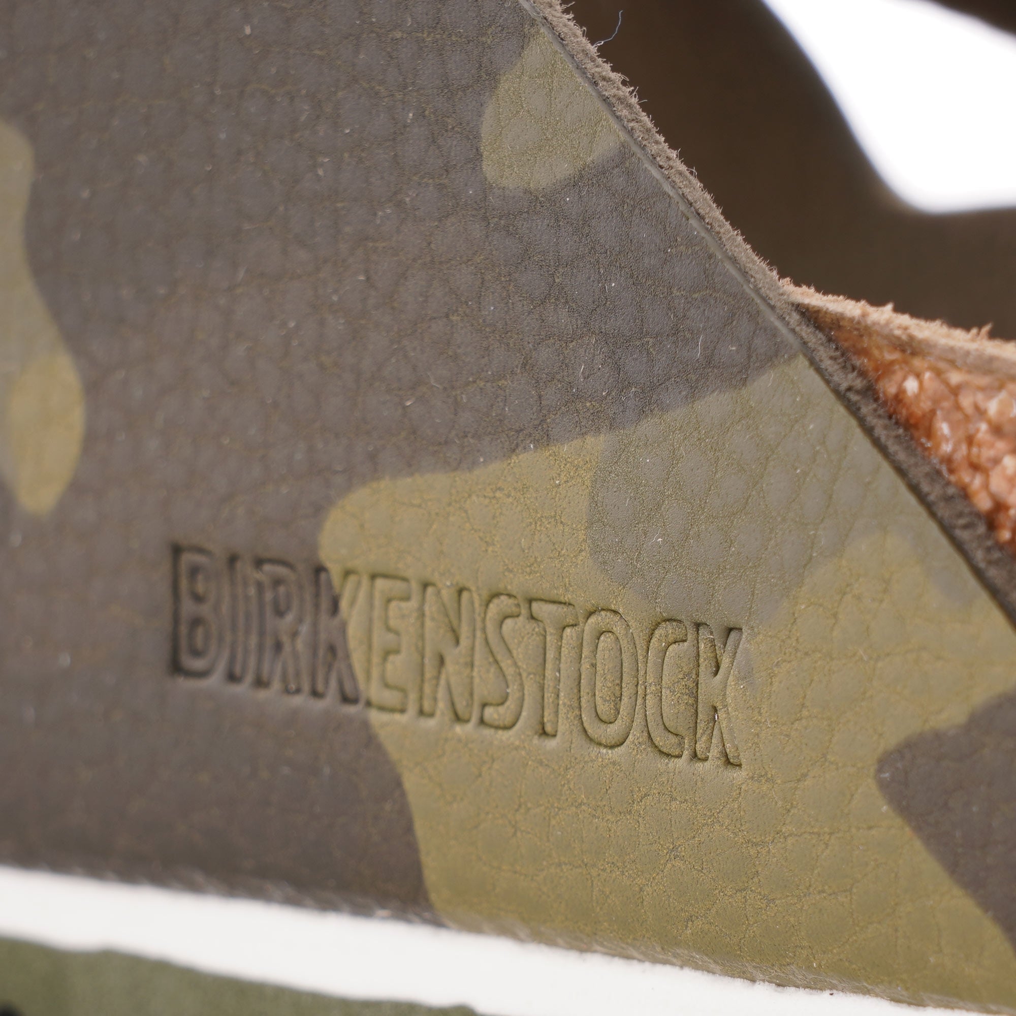 Close-up of the embossed Birkenstock logo on a green camouflage sandal.