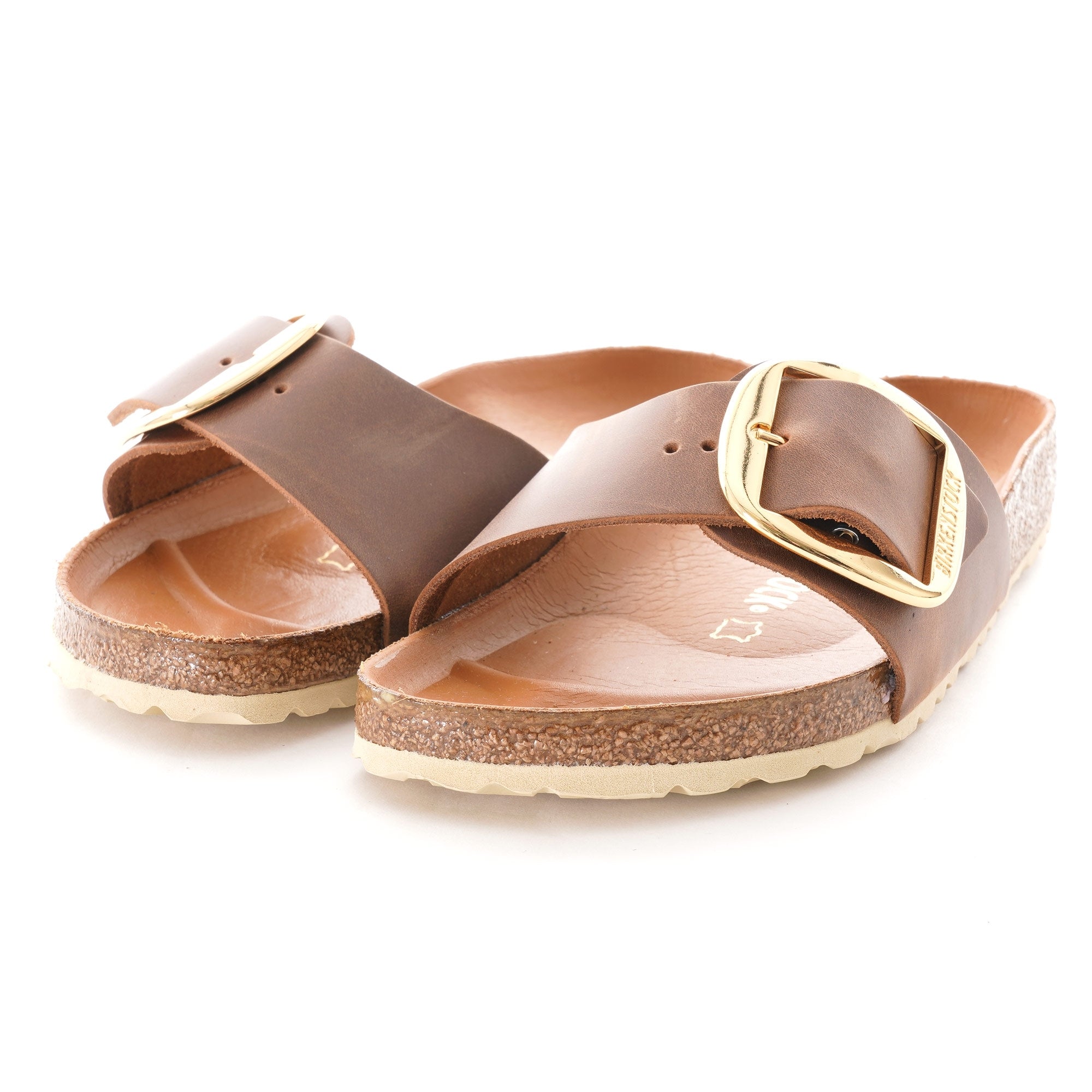Pair of brown sandals with gold buckles on a white background.
