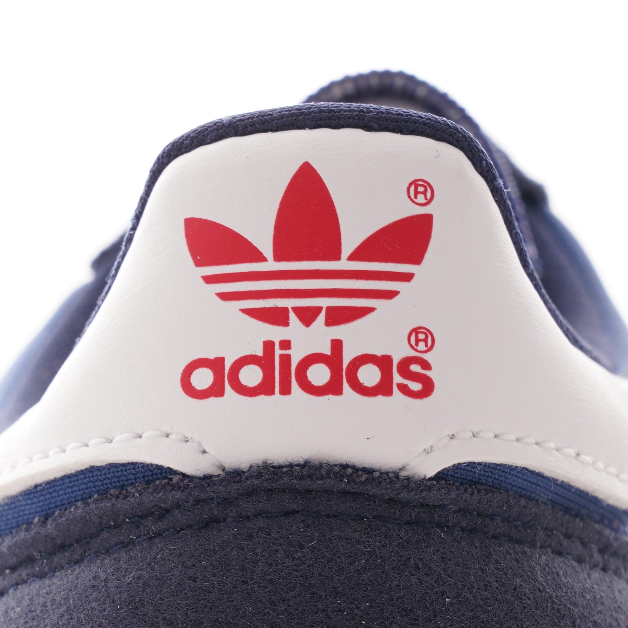 The red Adidas Trefoil logo on the heel of a navy blue TRX Soulround shoe.