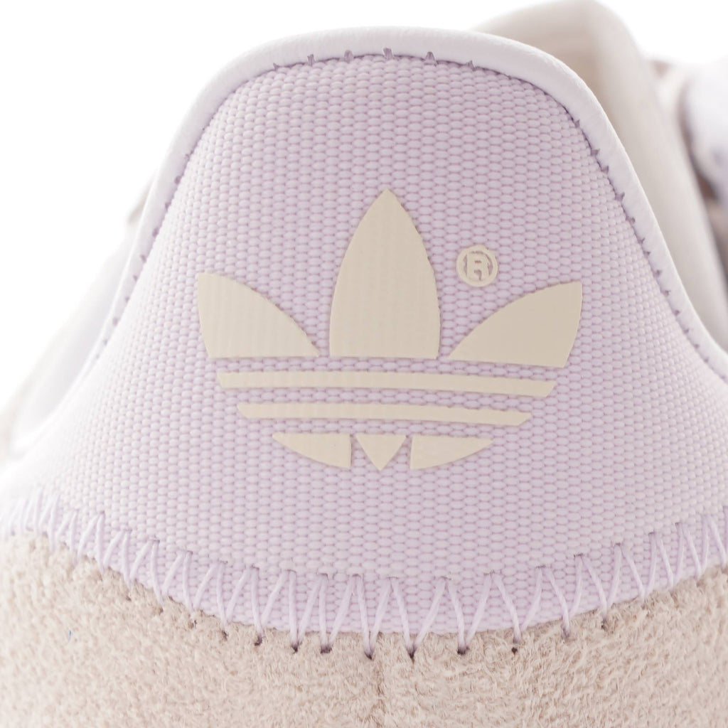 Close-up of the Adidas logo on the light purple heel tab of a trainer.