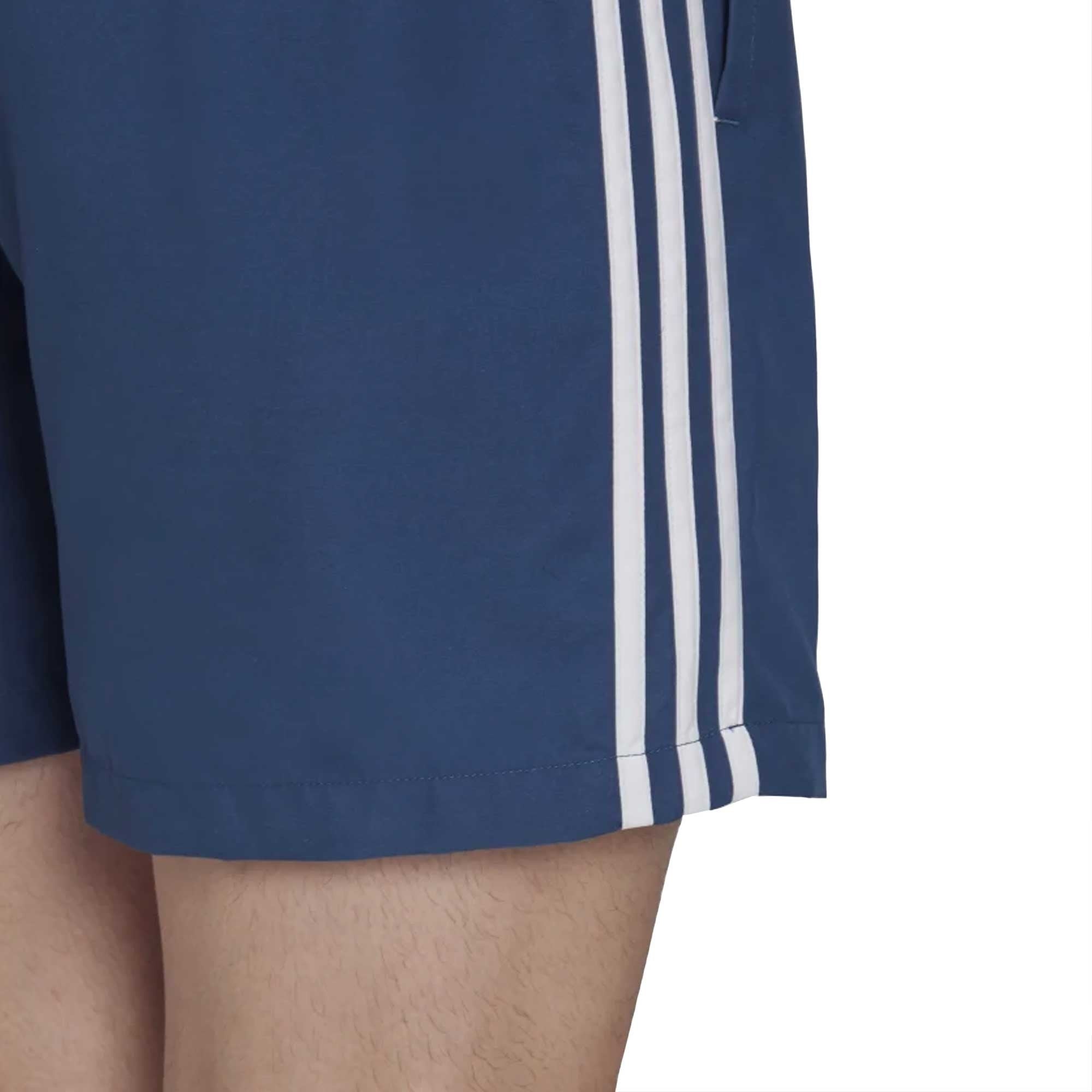 Close-up of the leg of navy blue Adidas 3-Stripes swim shorts.