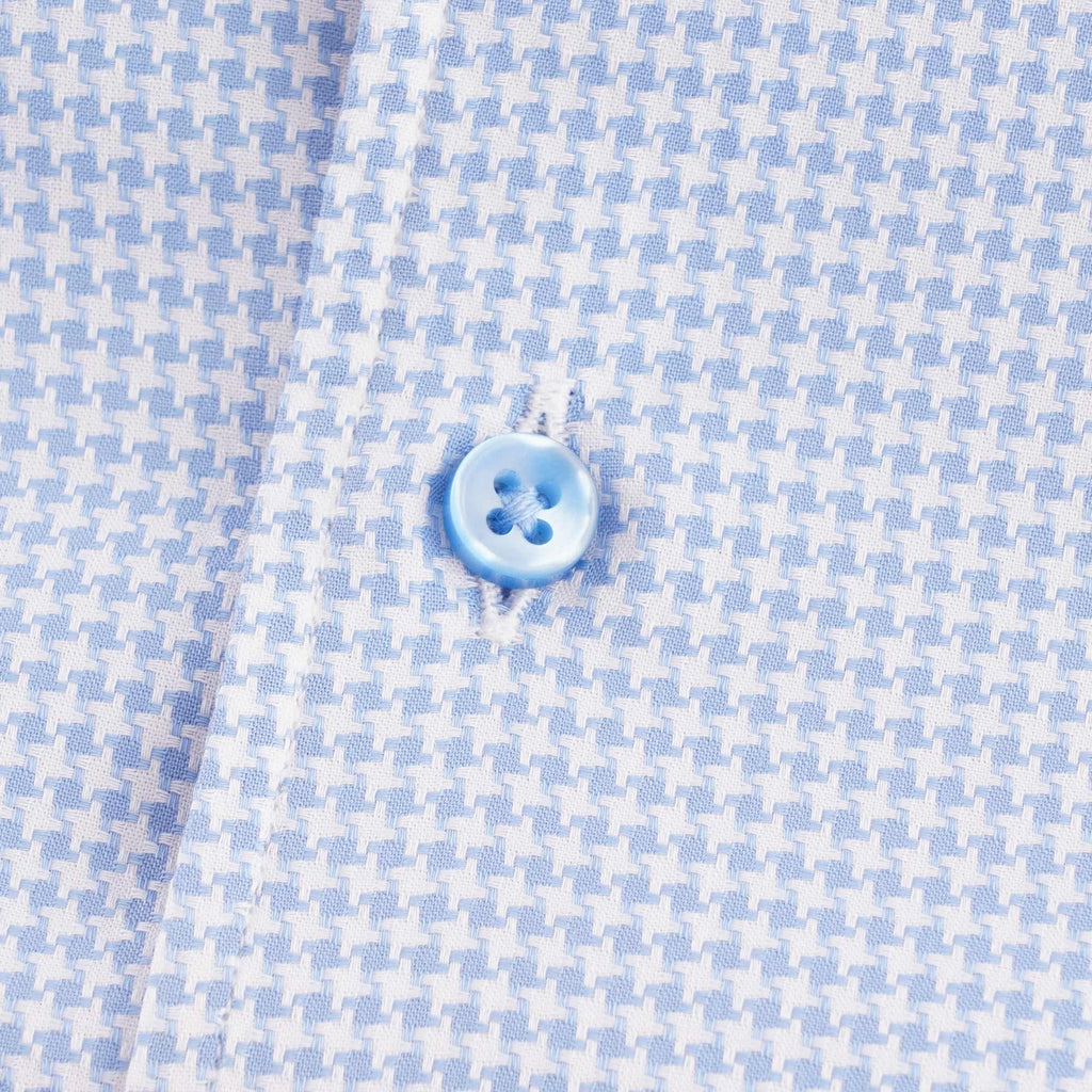 Close-up of a light blue button on the houndstooth patterned short-sleeved shirt.