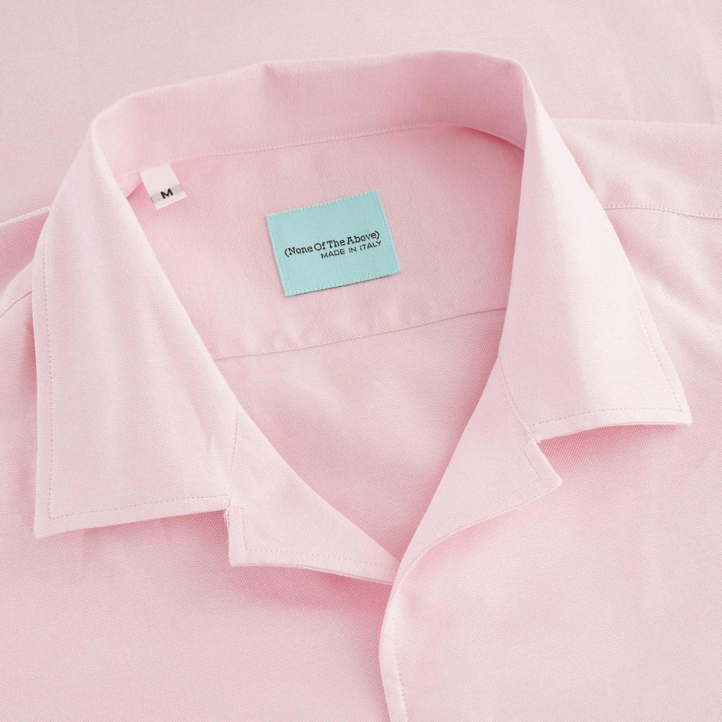Close-up of the pink shirt's collar and light blue brand label. 