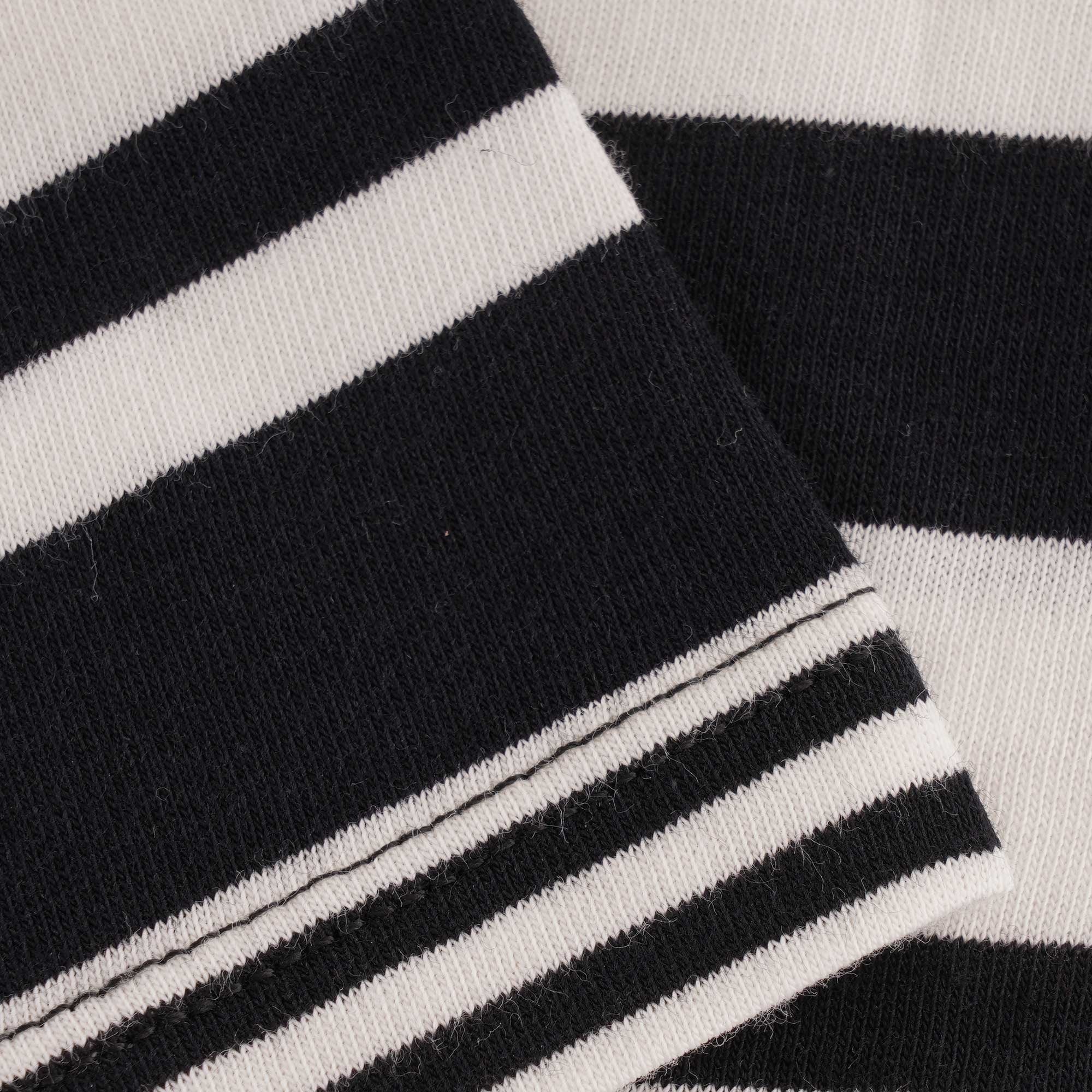 A close-up of the T-shirt's hem with black and white stripes and stitching detail.