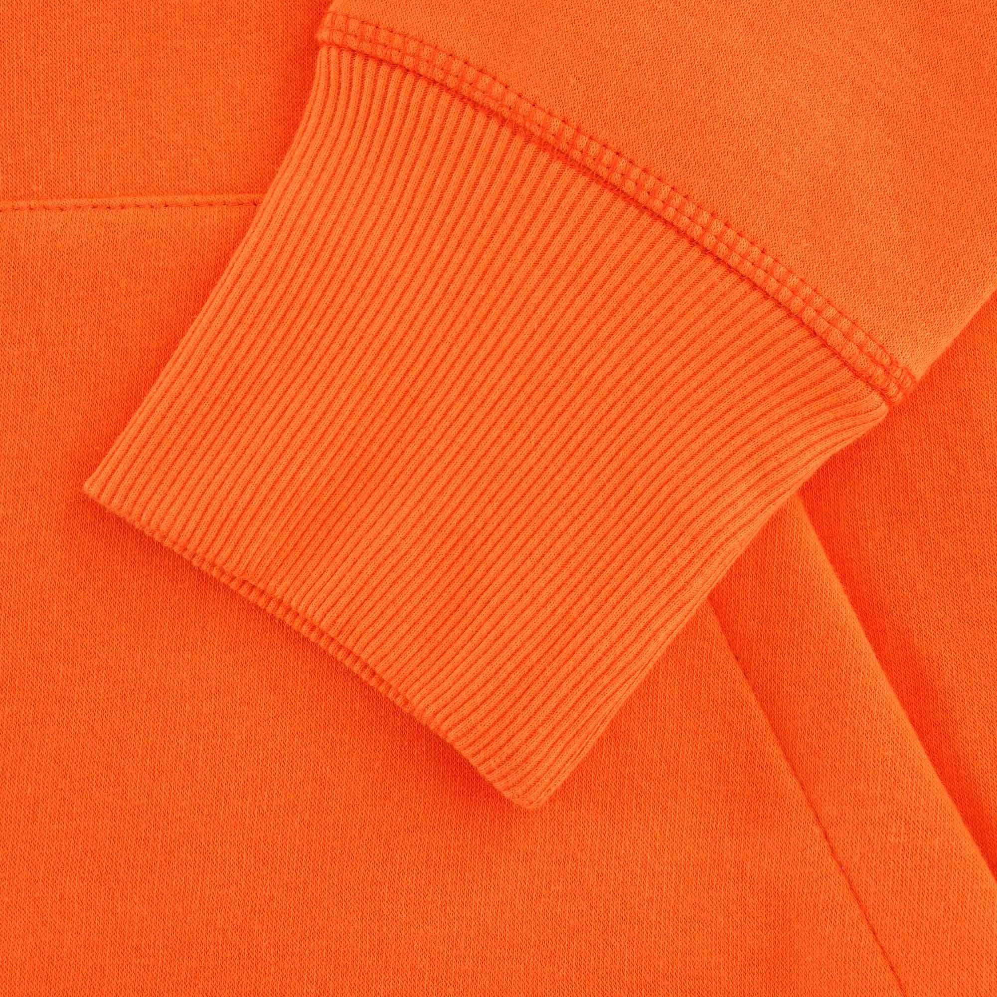 Close-up of the ribbed cuff on the orange hoodie's sleeve.