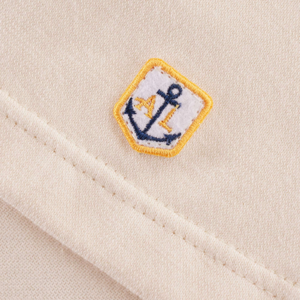 A detailed view of the small anchor logo on the bottom hem of the Loctudy T-Shirt.