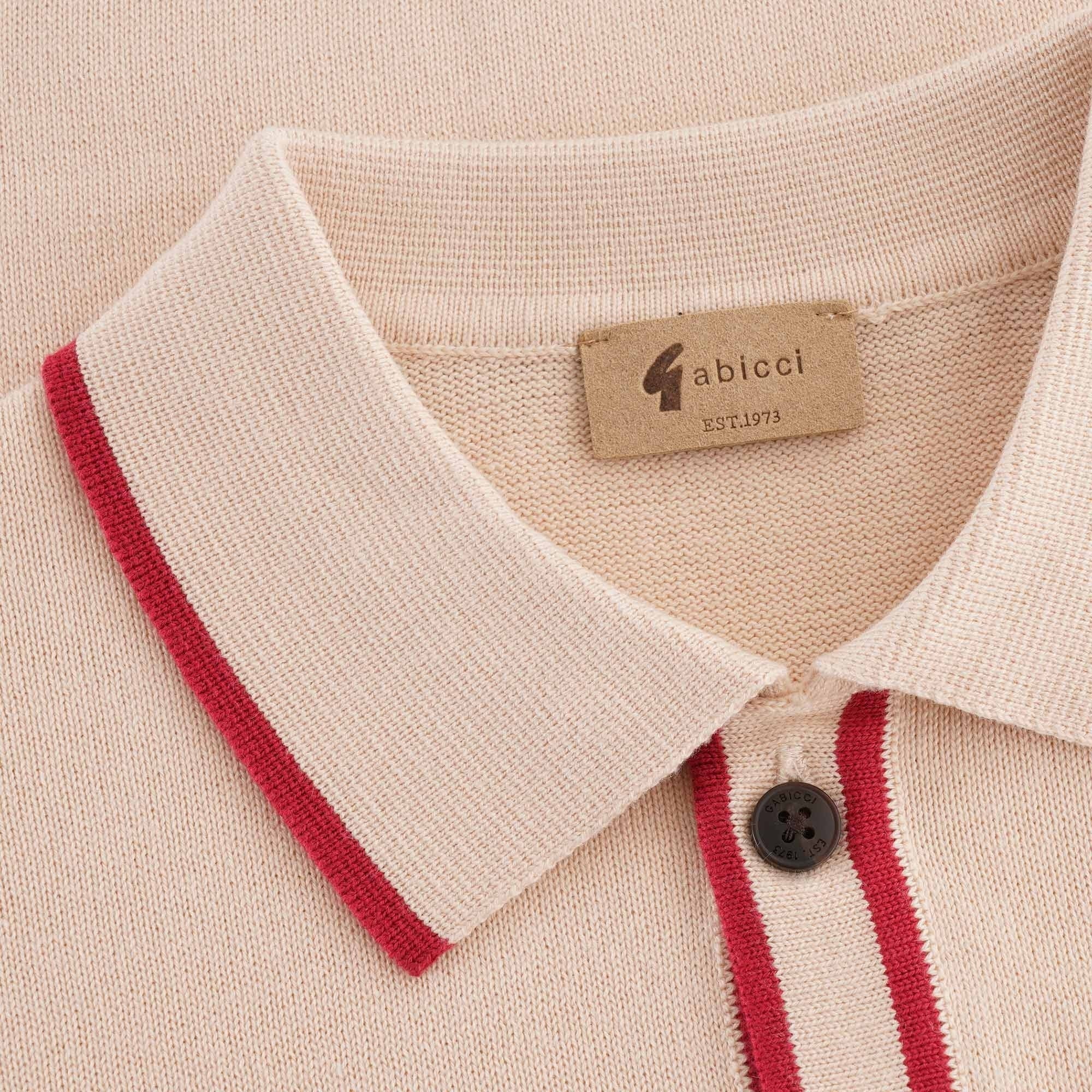 A close up of the collar of a beige polo shirt with a red trim.