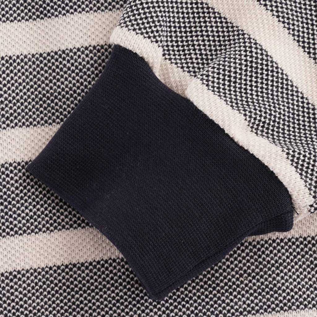 Close-up of the ribbed navy cuff and striped fabric of the long-sleeved polo shirt.