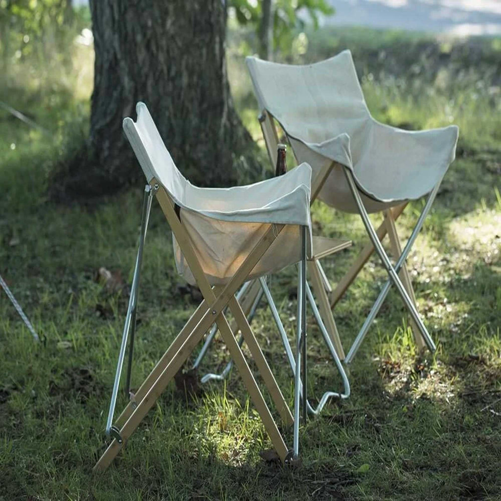 Two folding chairs set up on grass under a tree, ready for outdoor relaxation.