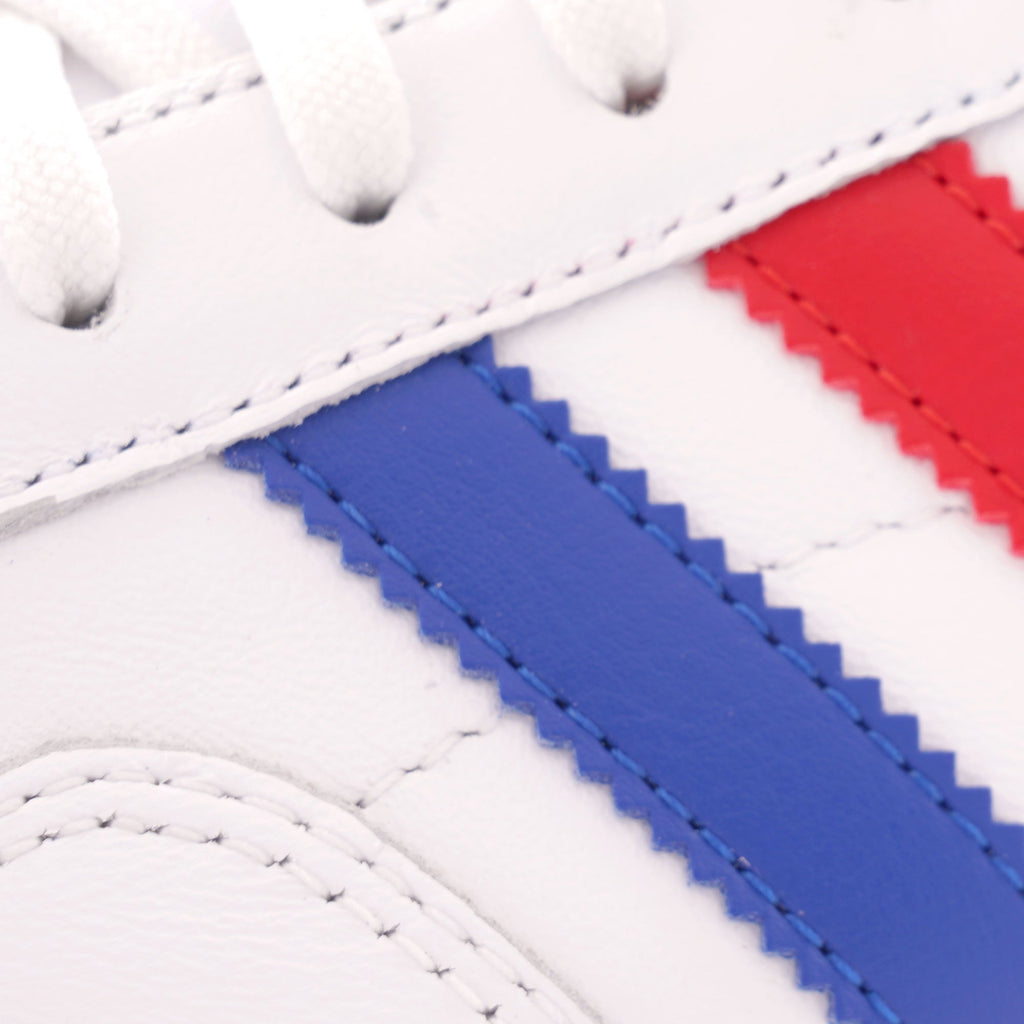 A close-up of the blue and red striped side of a white Adidas trainer.