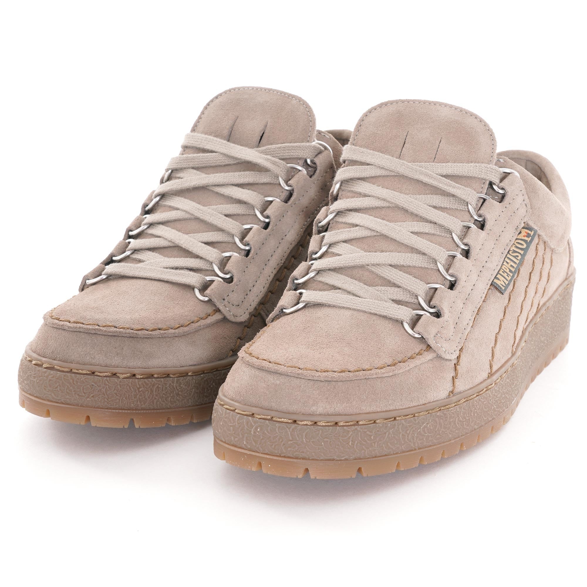 A pair of beige suede shoes with light coloured laces and thick soles, viewed from an angle.
