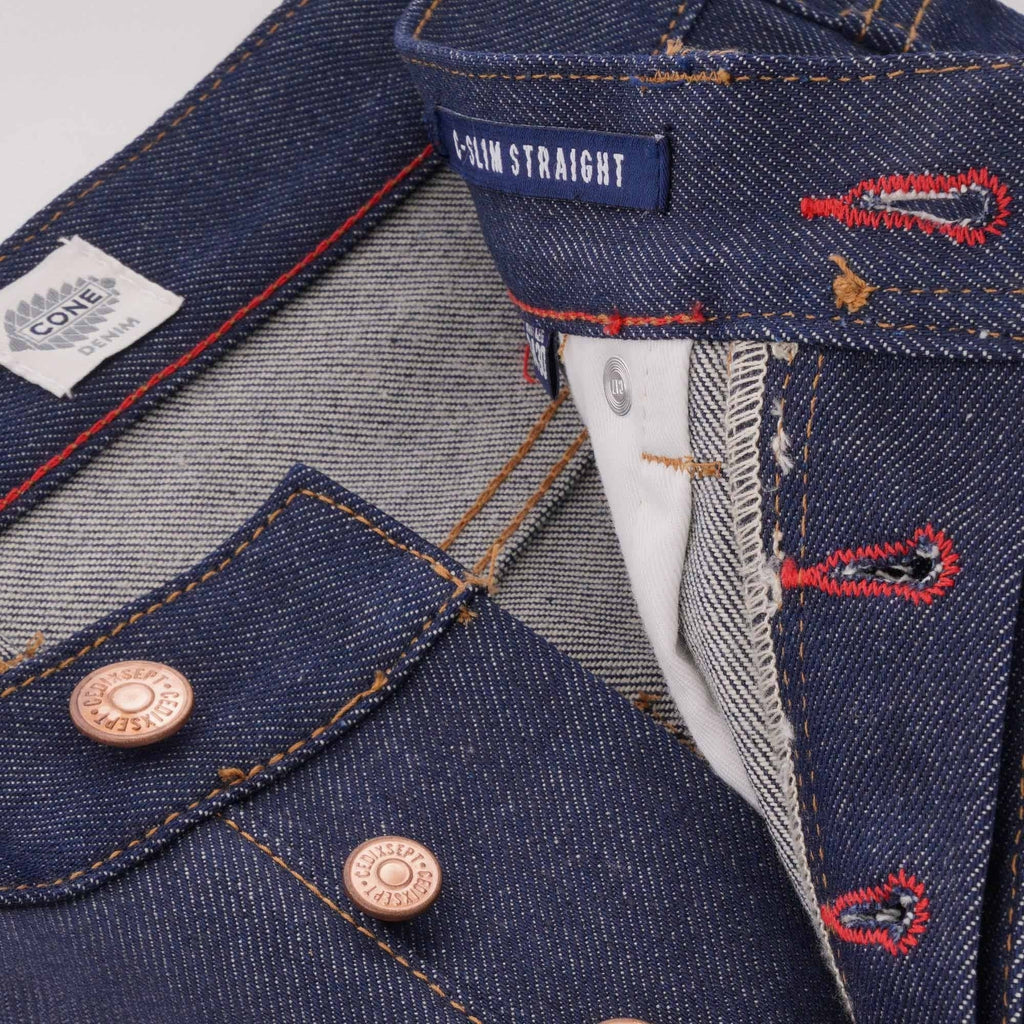 Close-up of the button fly closure on C17 jeans, showing copper buttons and red stitching.