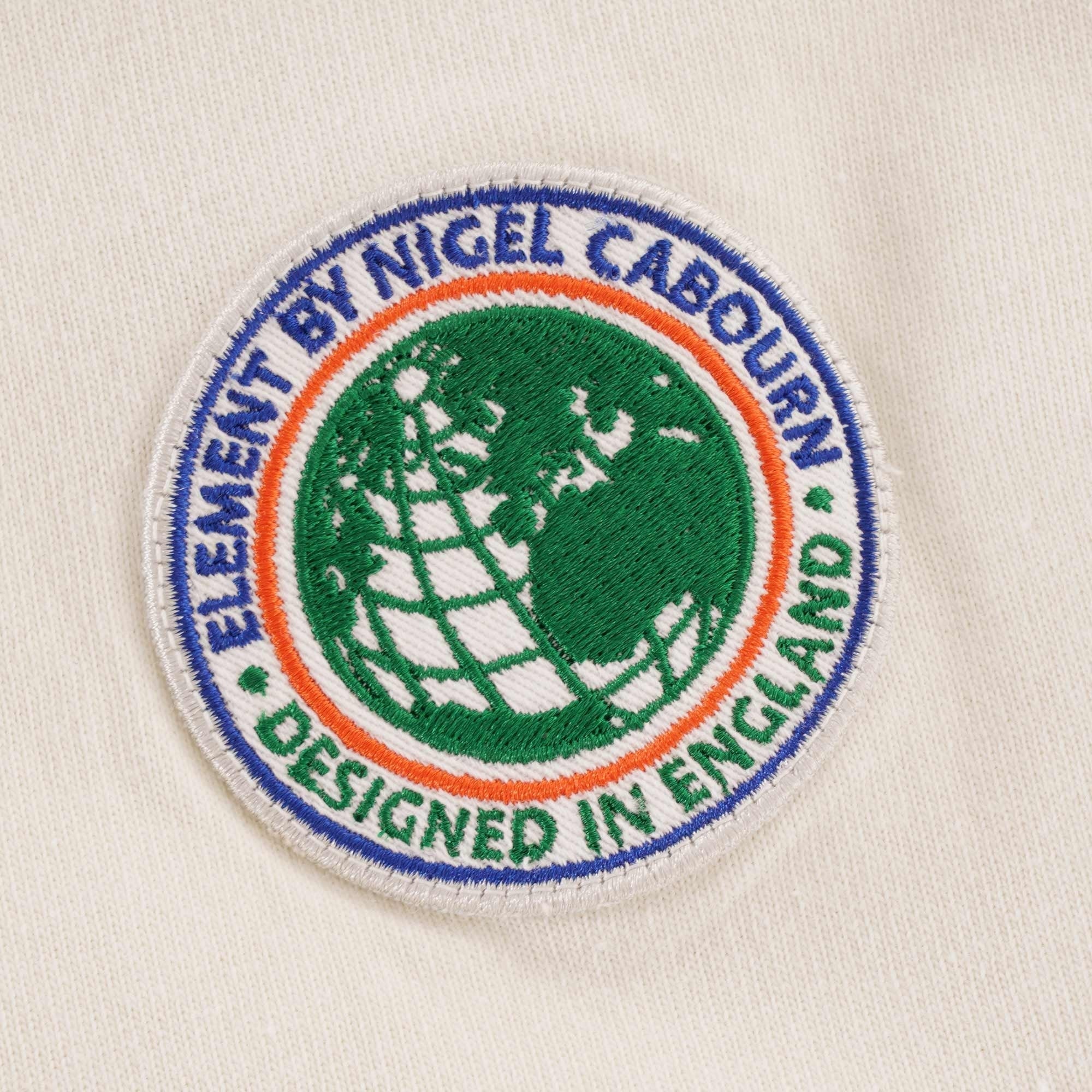 A close-up of the circular chest logo, featuring a globe design and text.