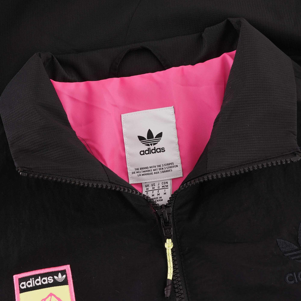 The collar of a black Adidas jacket, showing the pink interior and Adidas neck label.