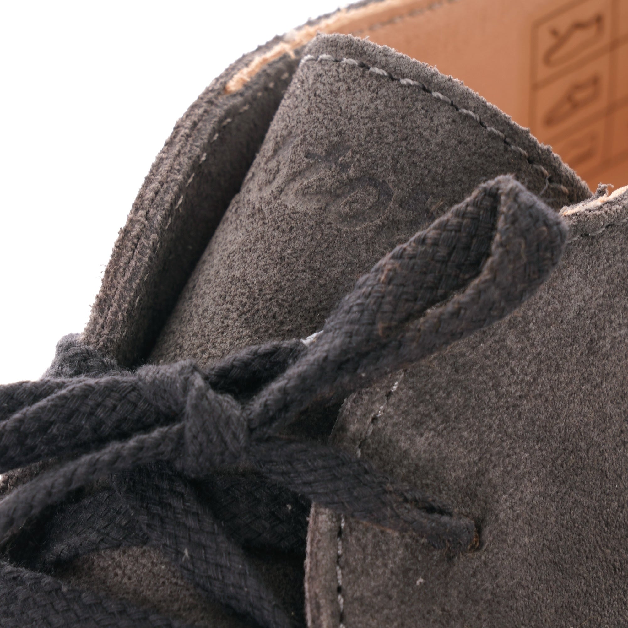 Close-up of the grey suede upper and black laces of a desert boot.