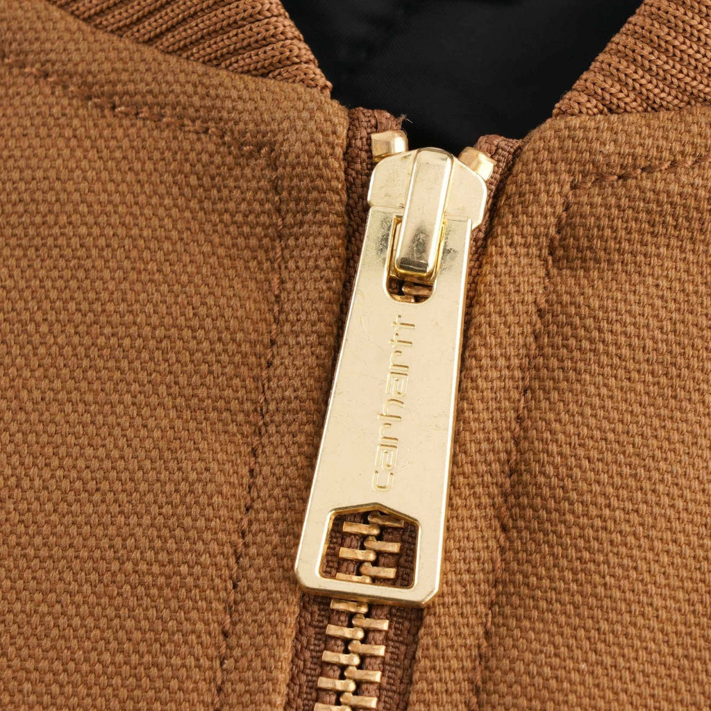 Detail of the golden Carhartt branded zipper pull on the brown vest.