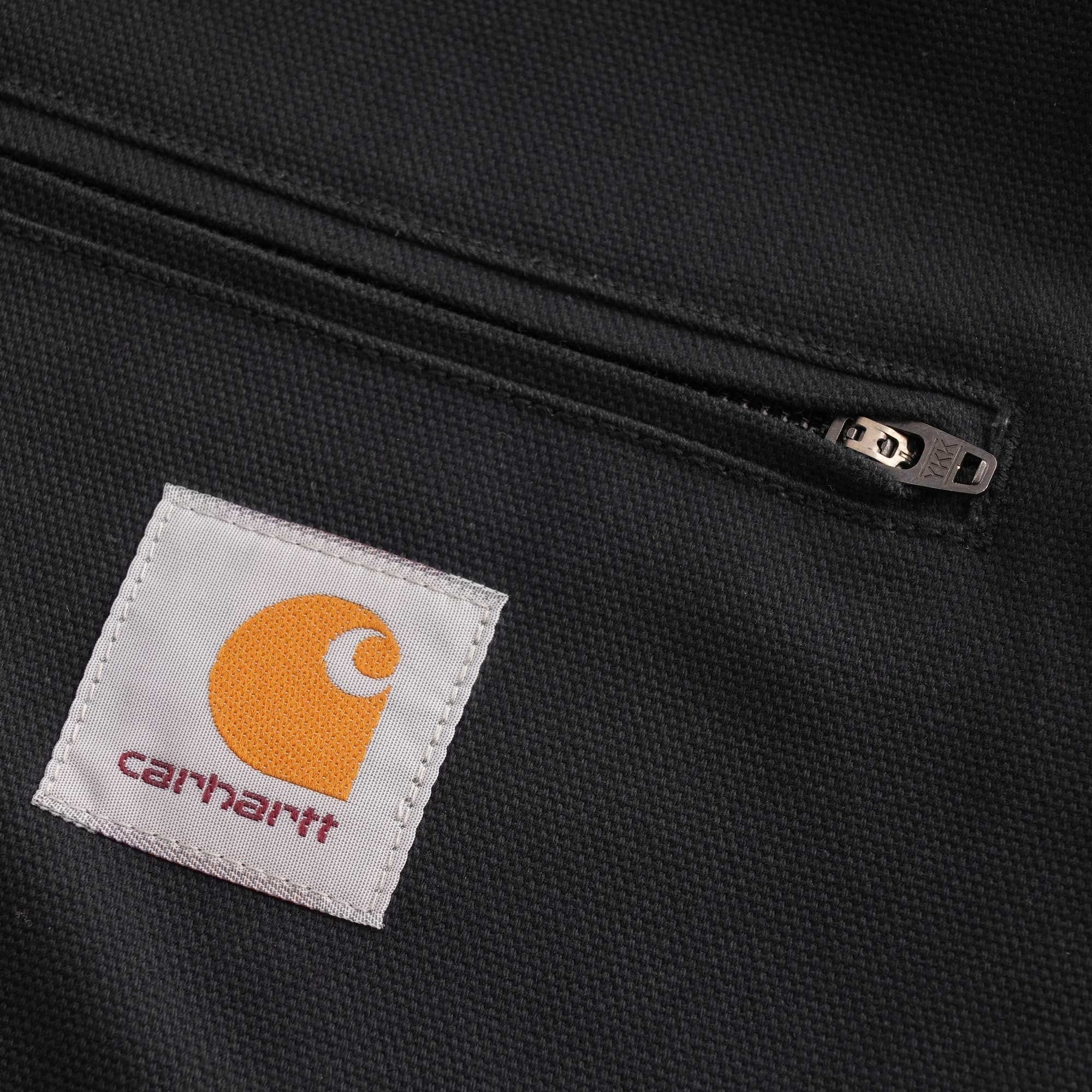 Close-up of the Carhartt WIP logo patch and zipped chest pocket on a black jacket.