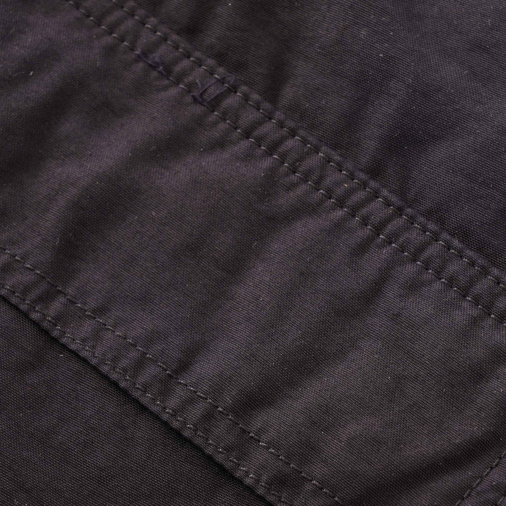 A close-up of the textured fabric and stitching on the dark grey cargo trousers.