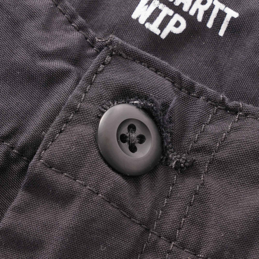 A close-up of a button and part of the Carhartt WIP logo on the trousers.