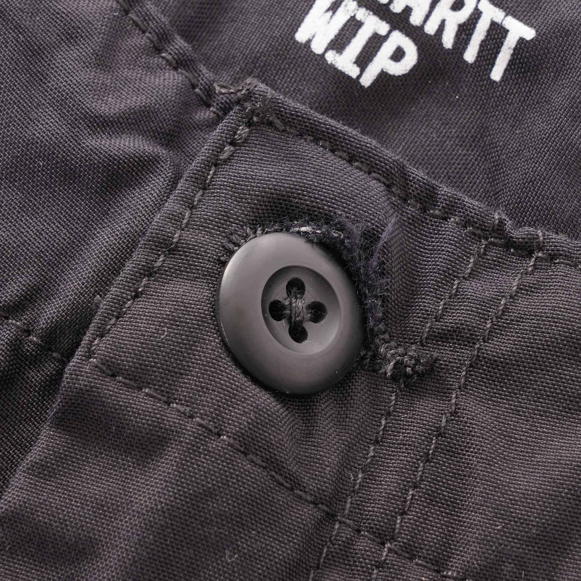 A close-up of a button and part of the Carhartt WIP logo on the trousers.