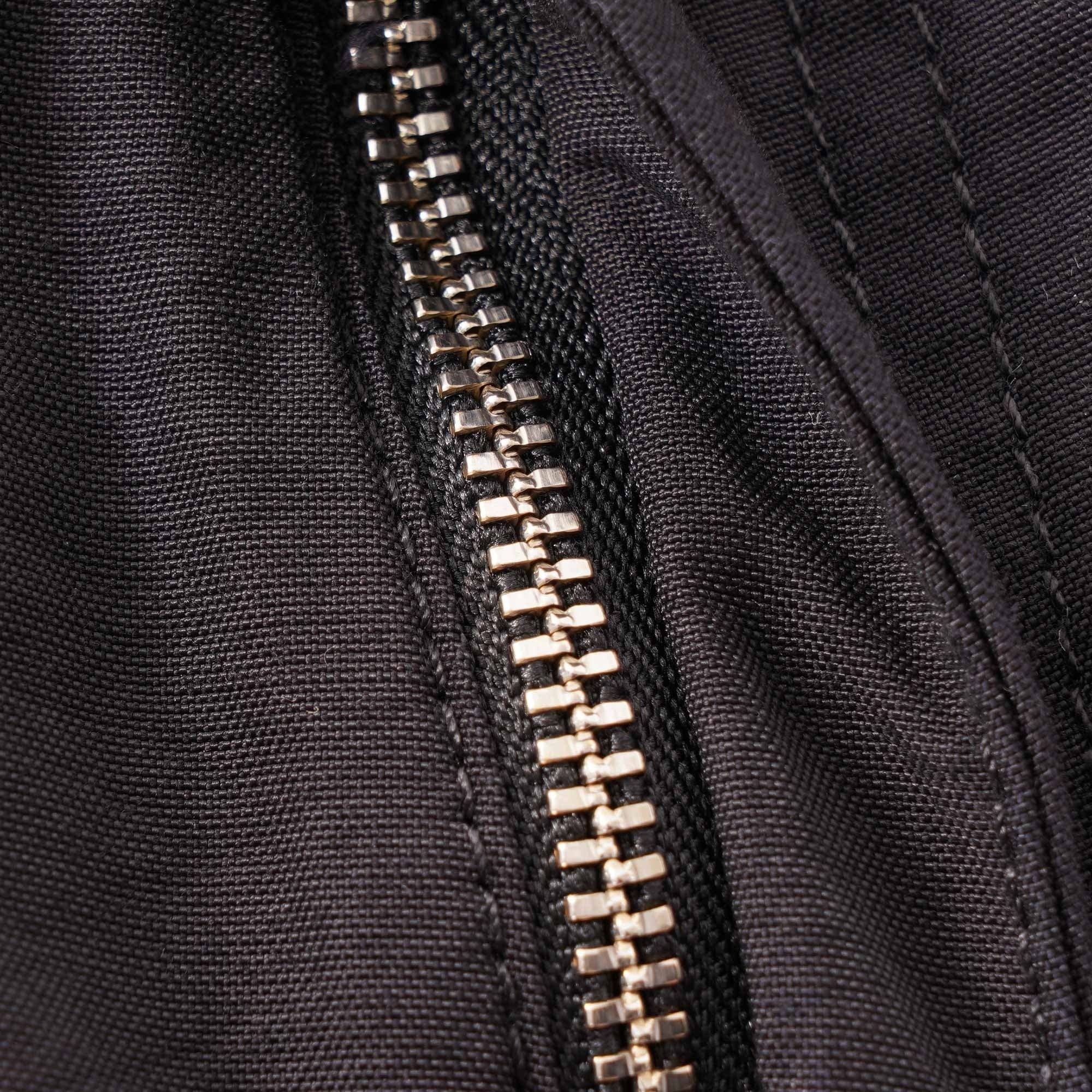 A close-up of the silver zipper on the dark grey cargo trousers.