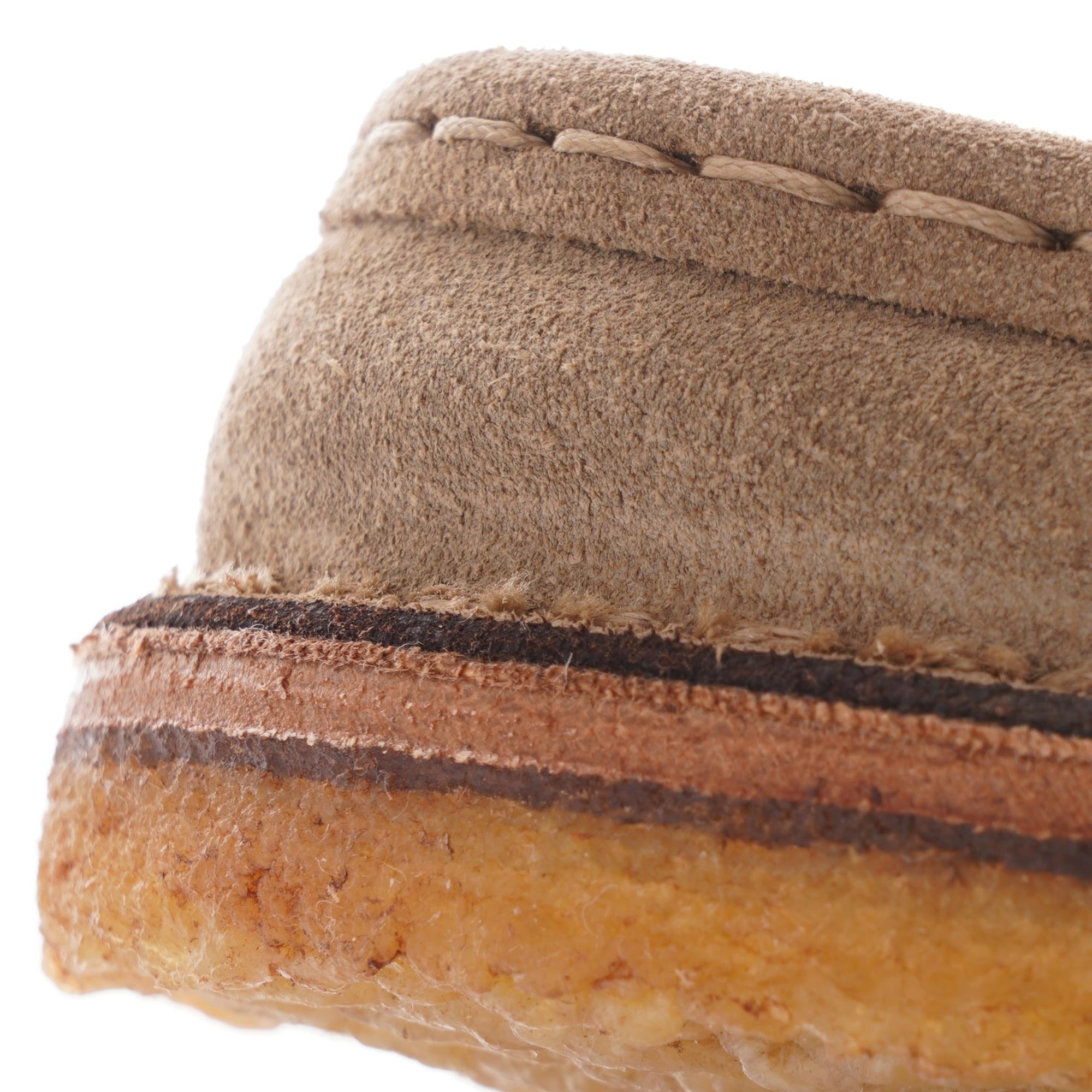 A close-up of the sole and stitching on a taupe suede shoe.