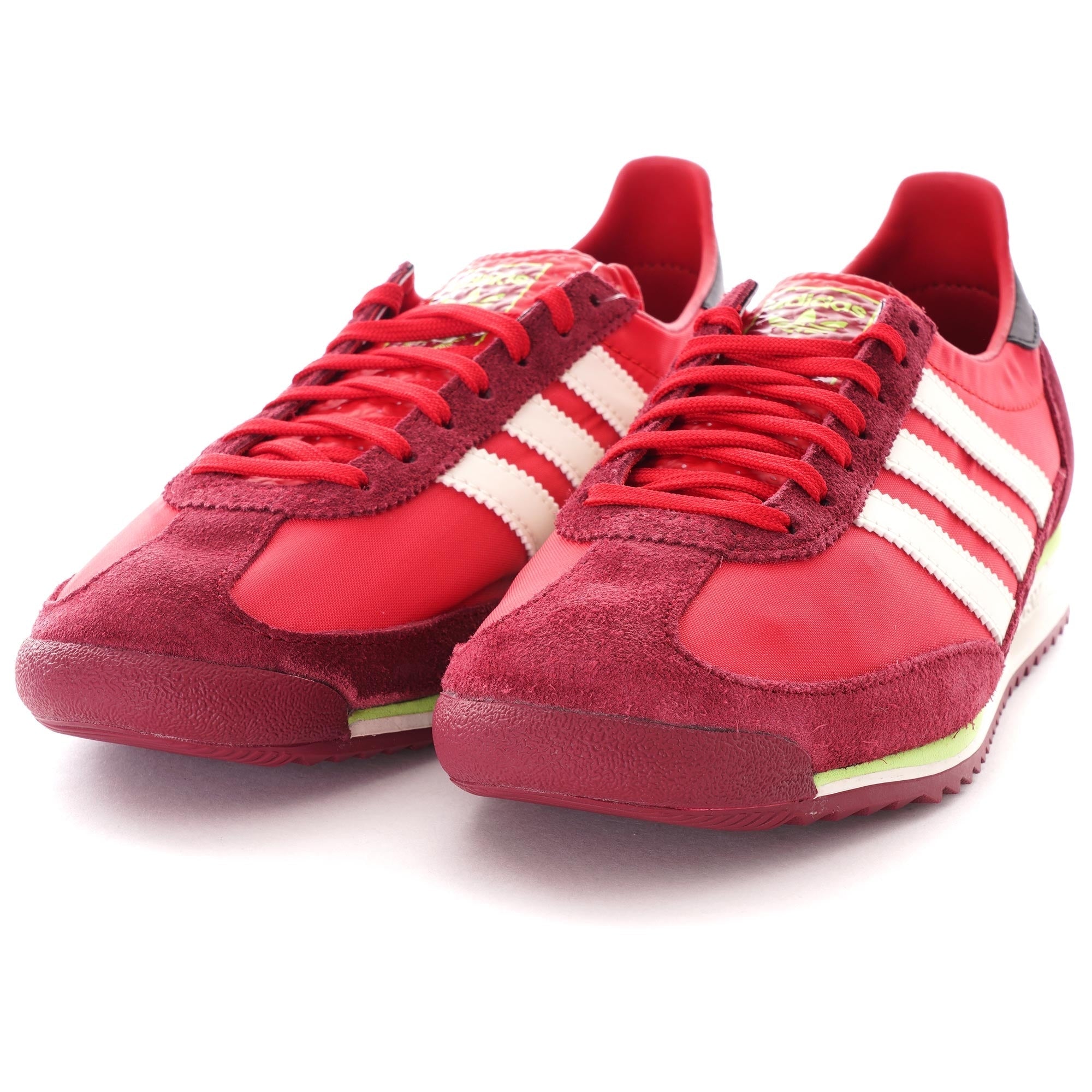 A slightly elevated shot of a pair of red adidas SL 72 RS trainers with white stripes.