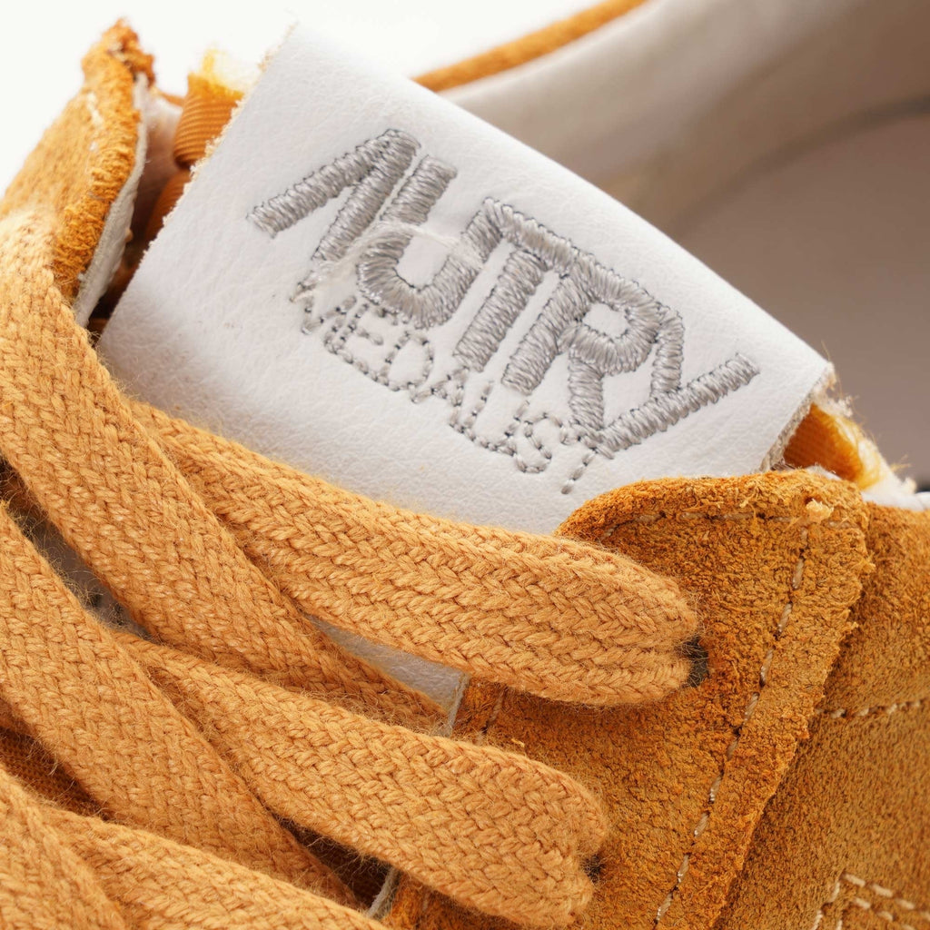 Close-up of the Autry logo on the tongue of a tan suede Autry Medalist Low trainer.