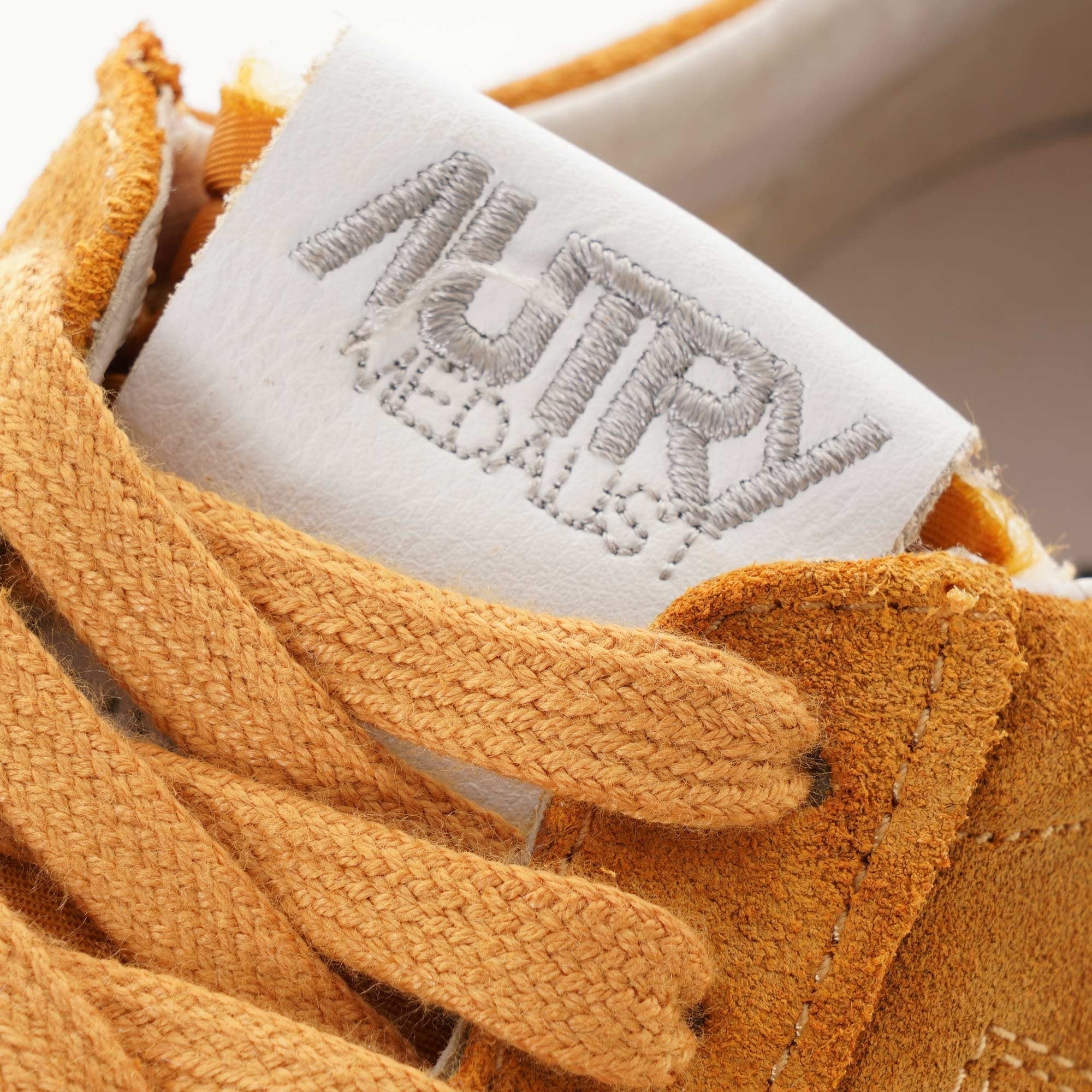 Close-up of the Autry logo on the tongue of a tan suede Autry Medalist Low trainer.