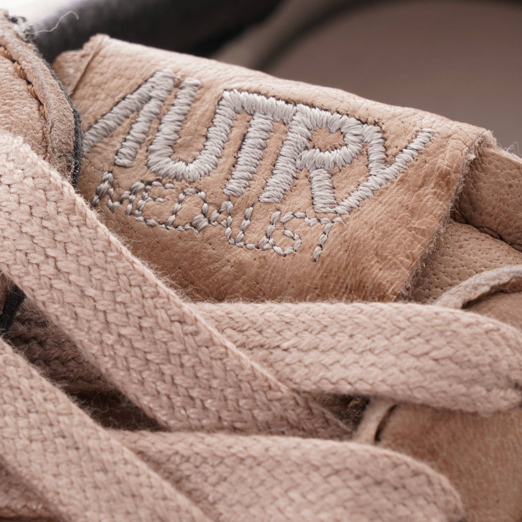 Close-up of the Autry logo embroidered on the tongue of a grey-brown leather sneaker.