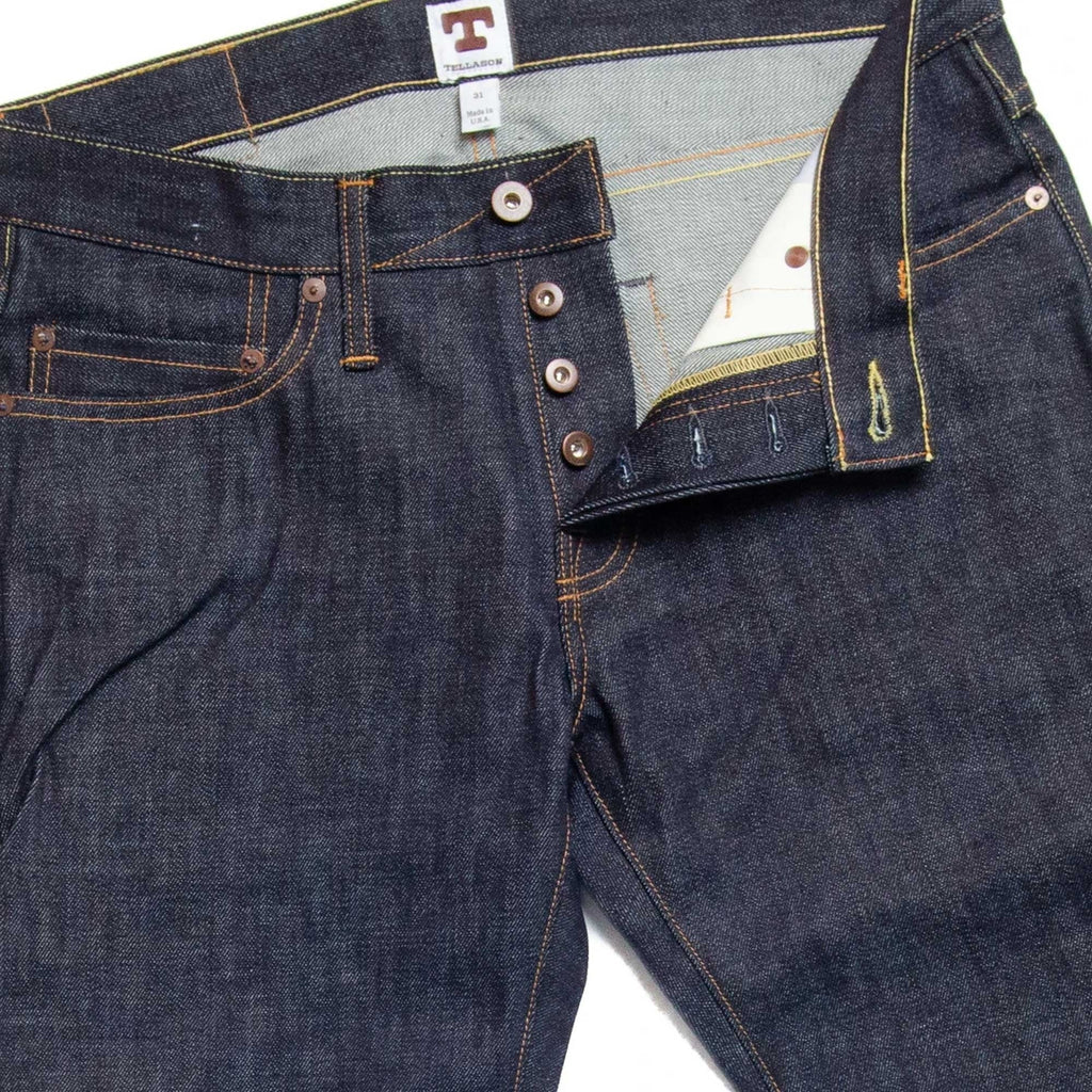 Close-up of the jeans' fly, highlighting the button closure and contrast stitching.
