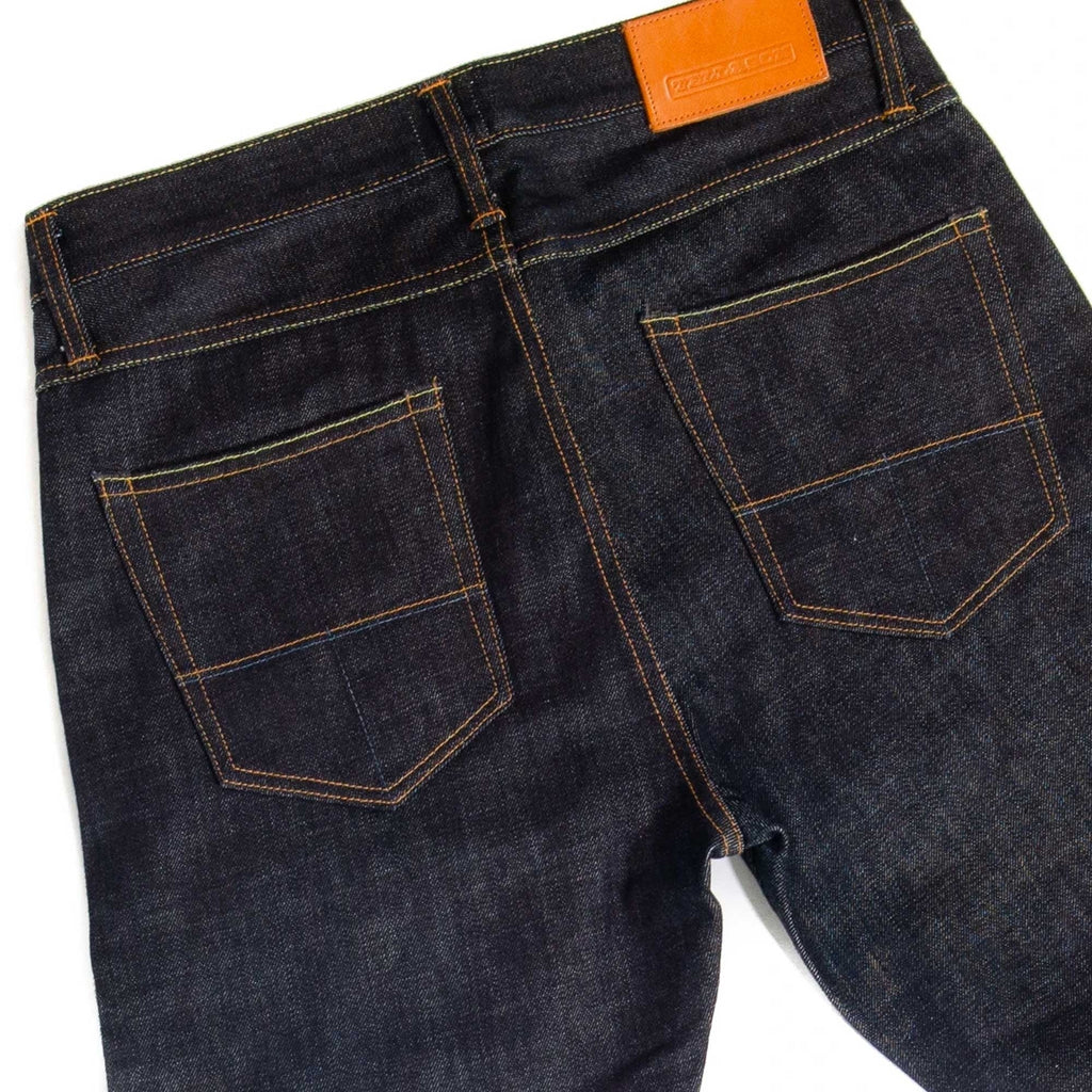 Rear view of dark wash selvedge denim jeans with prominent back pockets and leather patch.